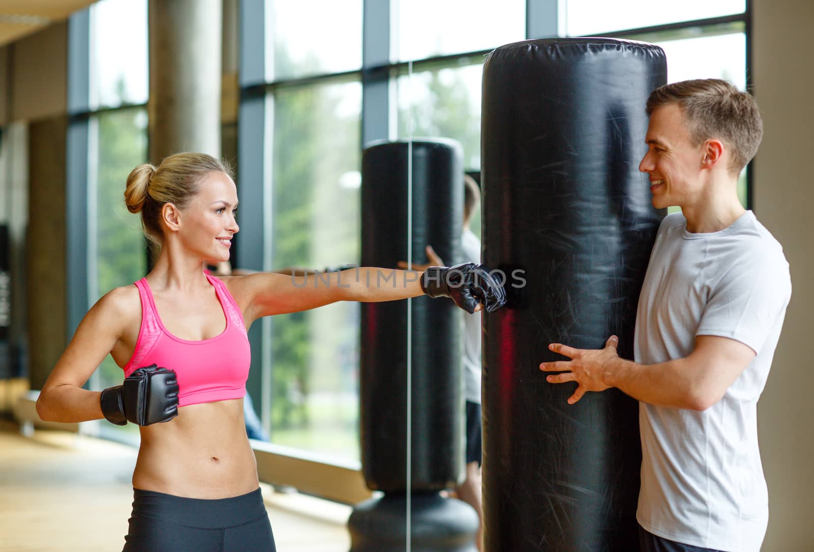 smiling woman with personal trainer boxing in gym by dolgachov