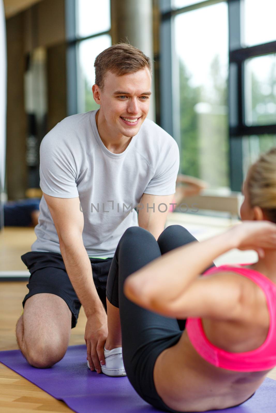 smiling woman with male trainer exercising in gym by dolgachov