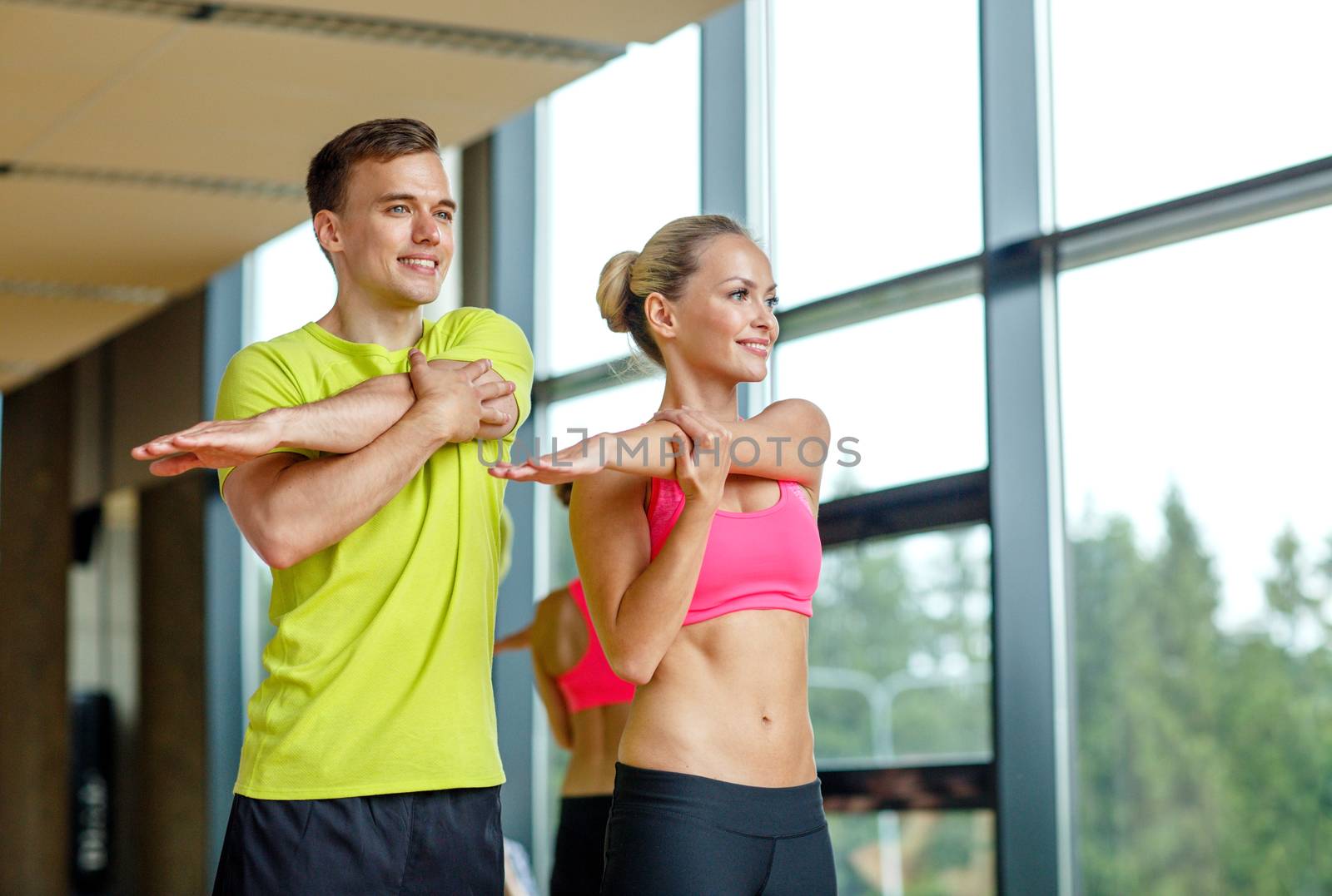 smiling man and woman exercising in gym by dolgachov