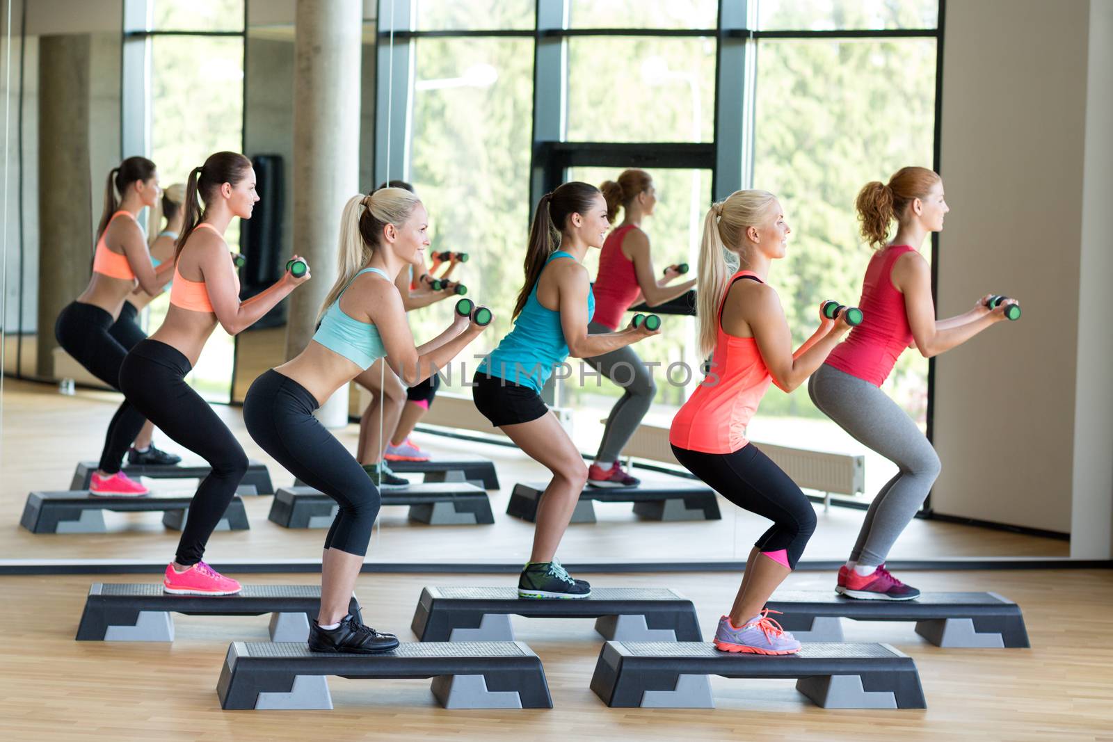 group of women with dumbbells and steppers by dolgachov