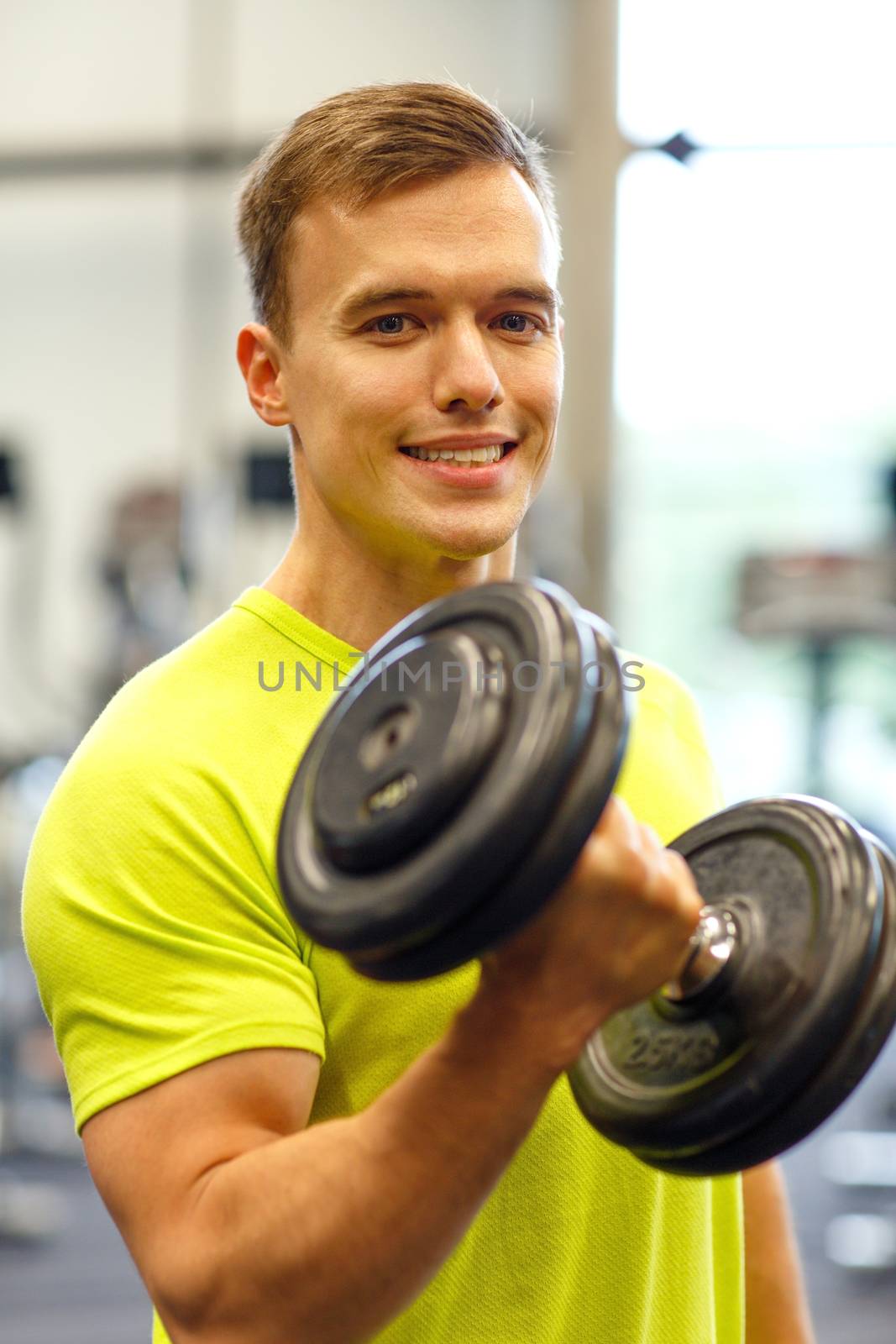 smiling man with dumbbell in gym by dolgachov