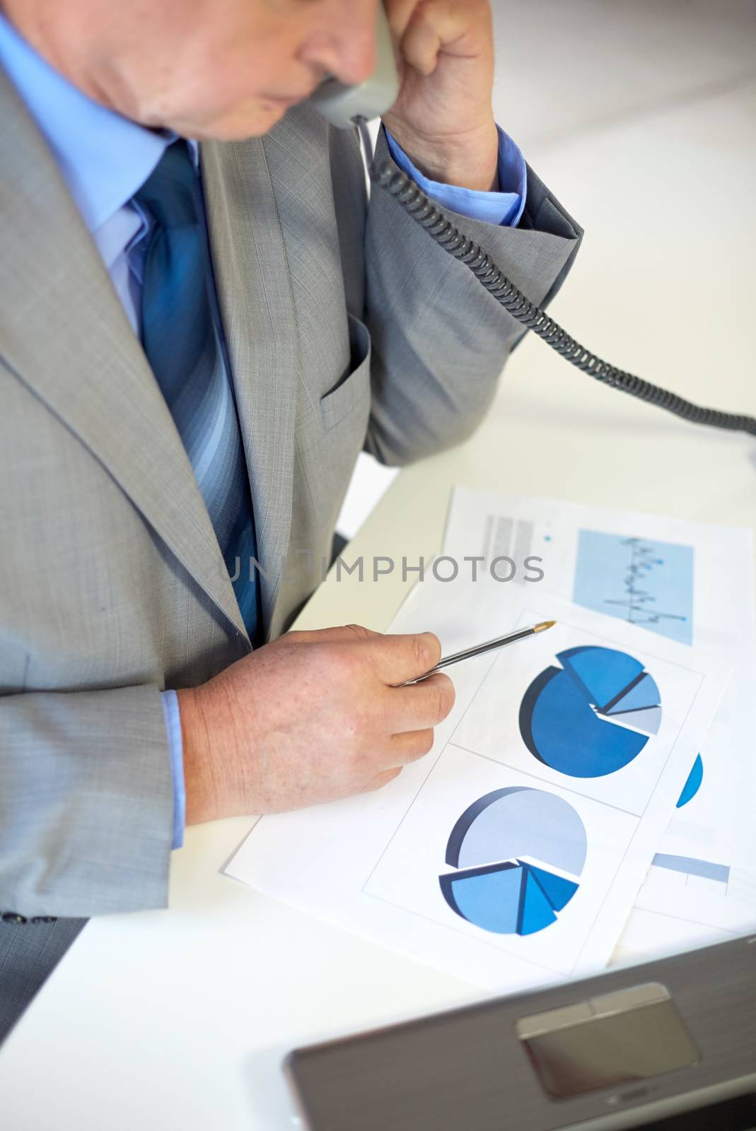 business, people and communication concept - close up of senior businessman with charts and papers calling on telephone