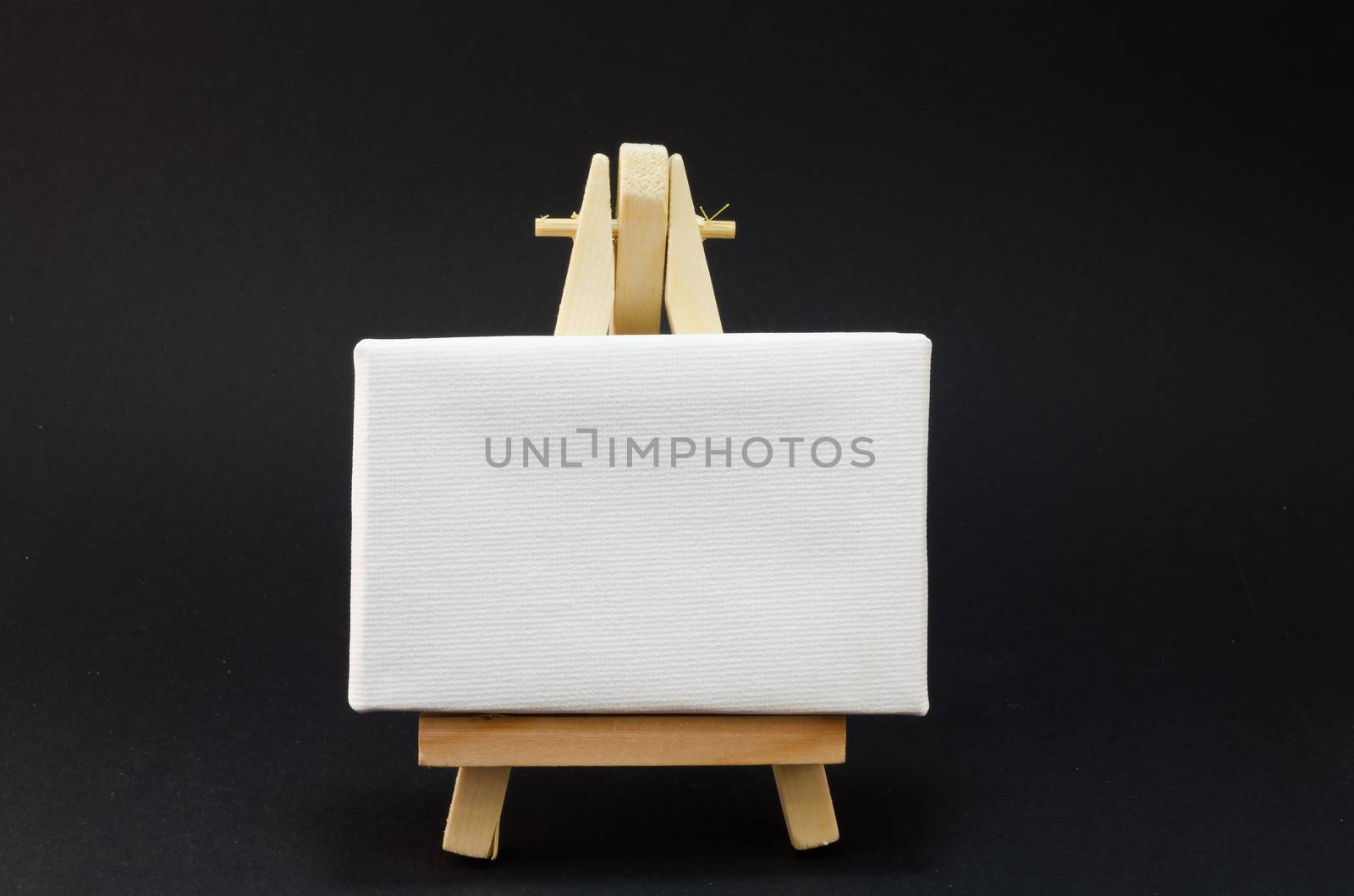 Miniature artist easel, isolated on black background.
