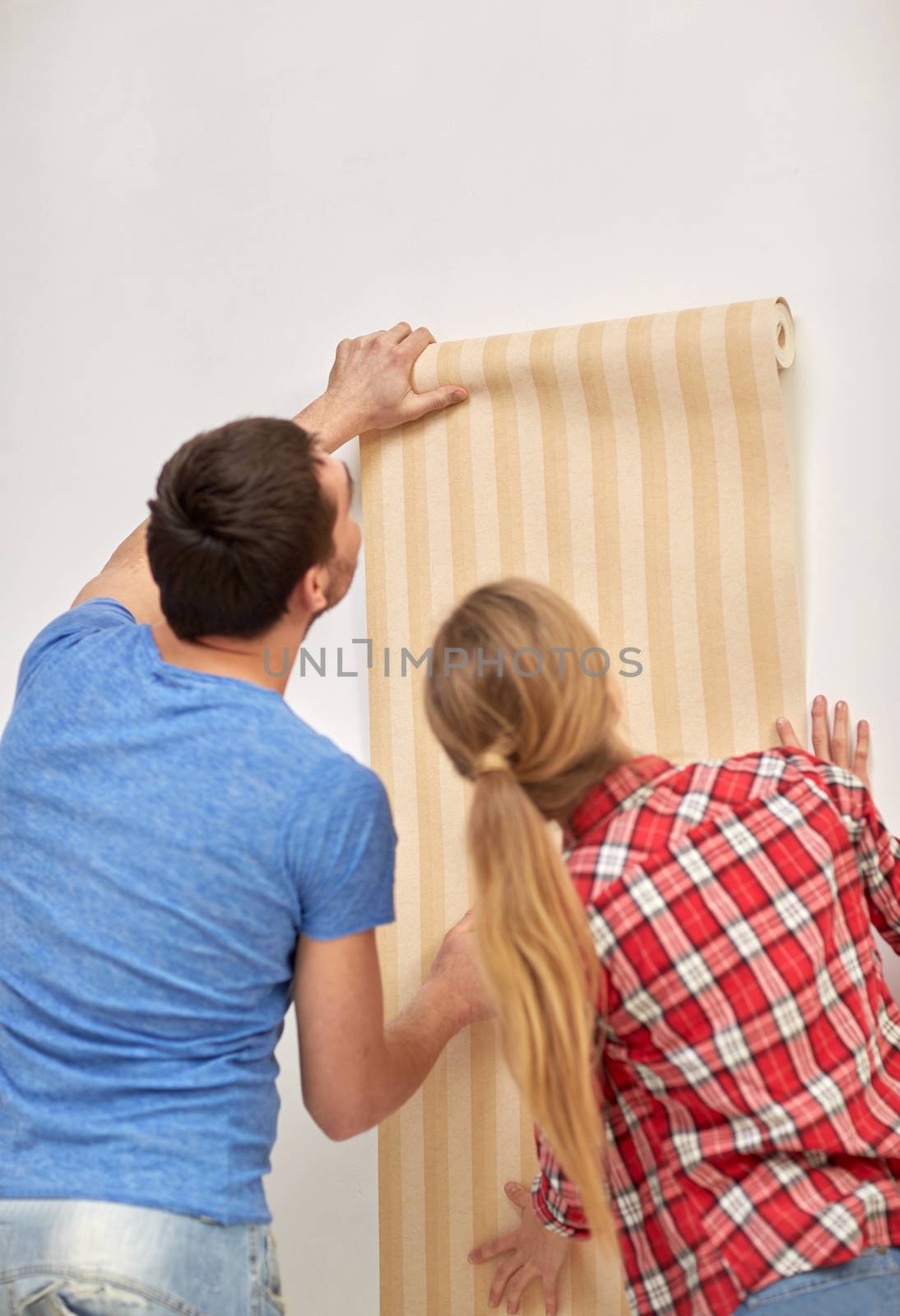 repair, renovation, building and people concept - close up of couple holding wallpaper at home
