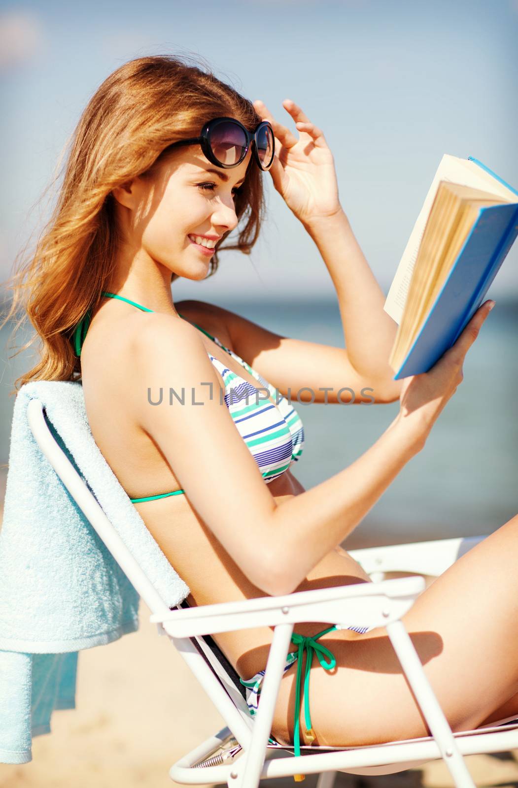 girl reading book on the beach chair by dolgachov