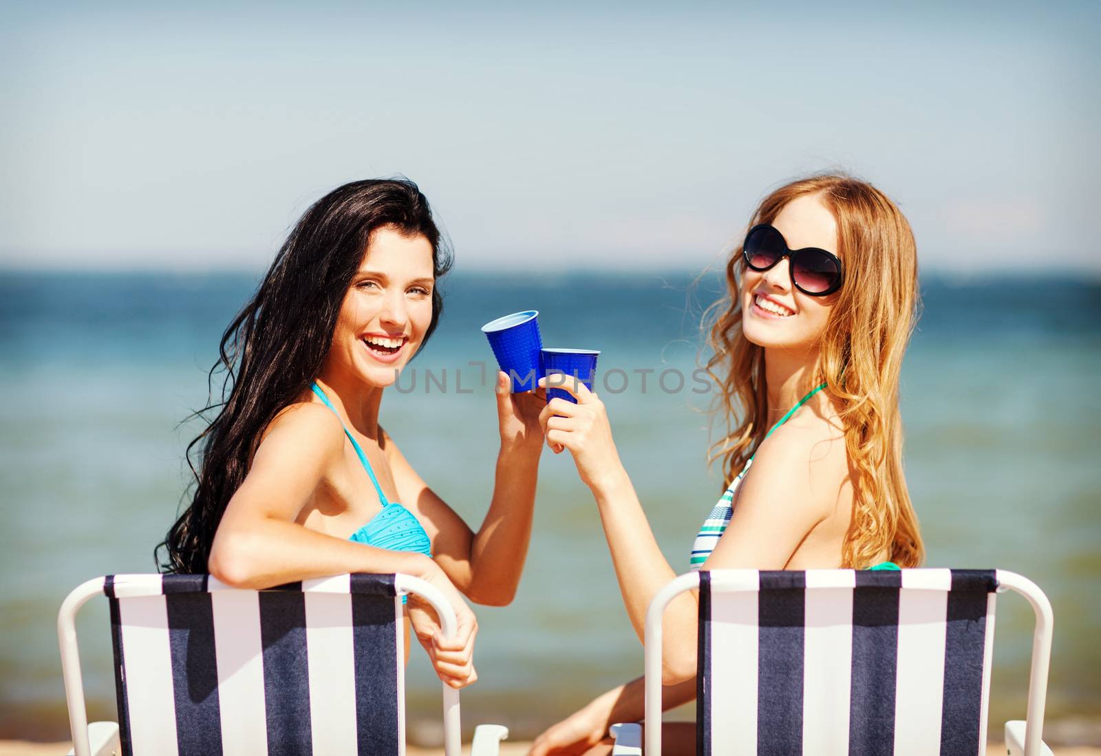 summer holidays and vacation - girls in bikinis with drinks on the beach chairs