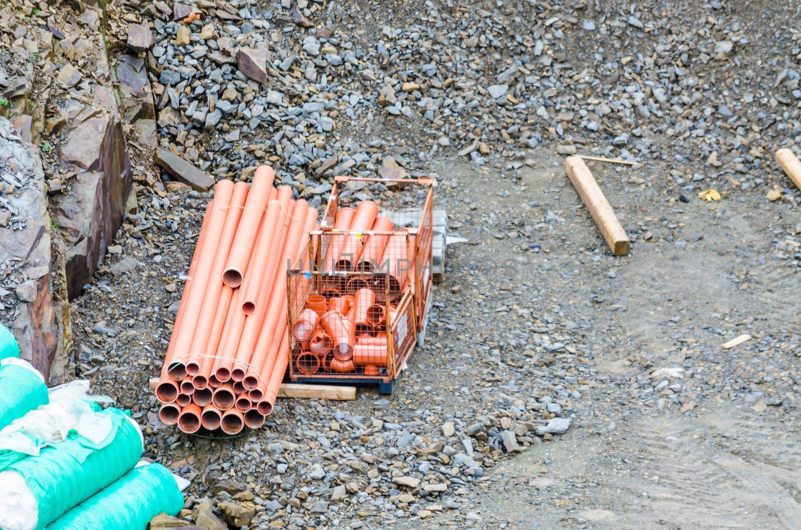 A pile of red drain pipes on a construction site