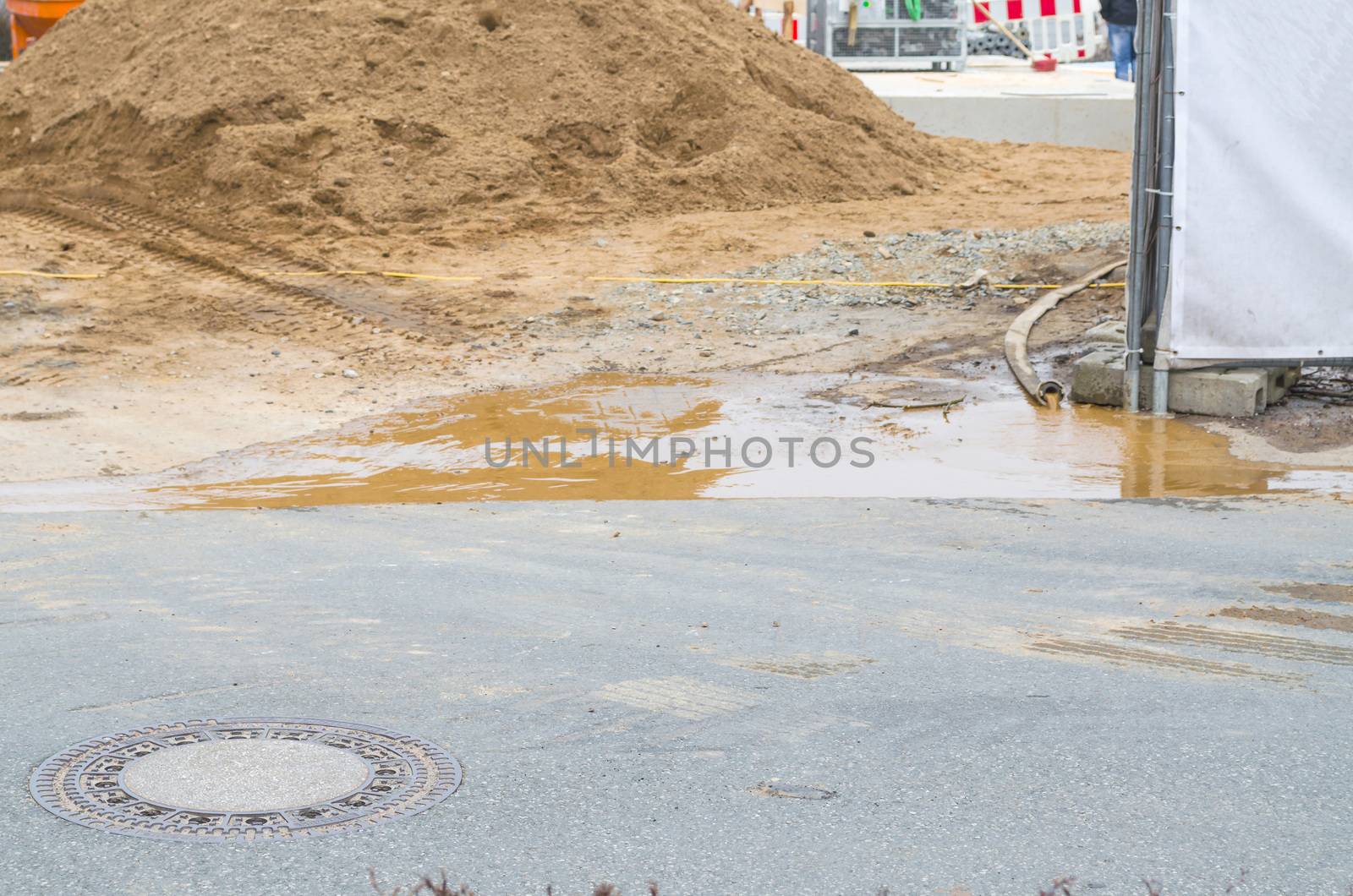 Urban Scene. A construction site is flooded. By a pump with hose water is pumped into the street.