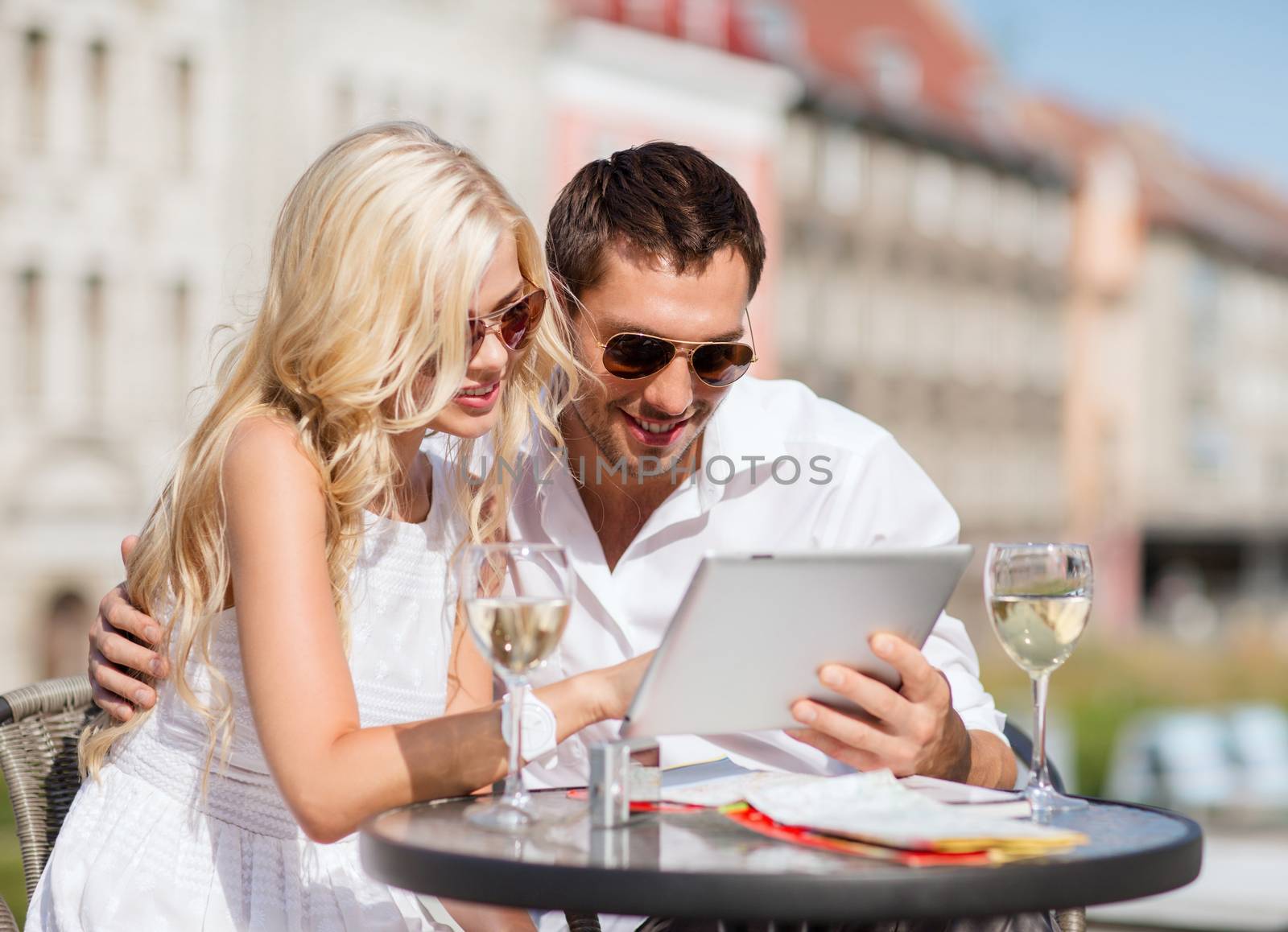 summer holidays, dating and technology concept - couple looking at tablet pc in cafe in the city