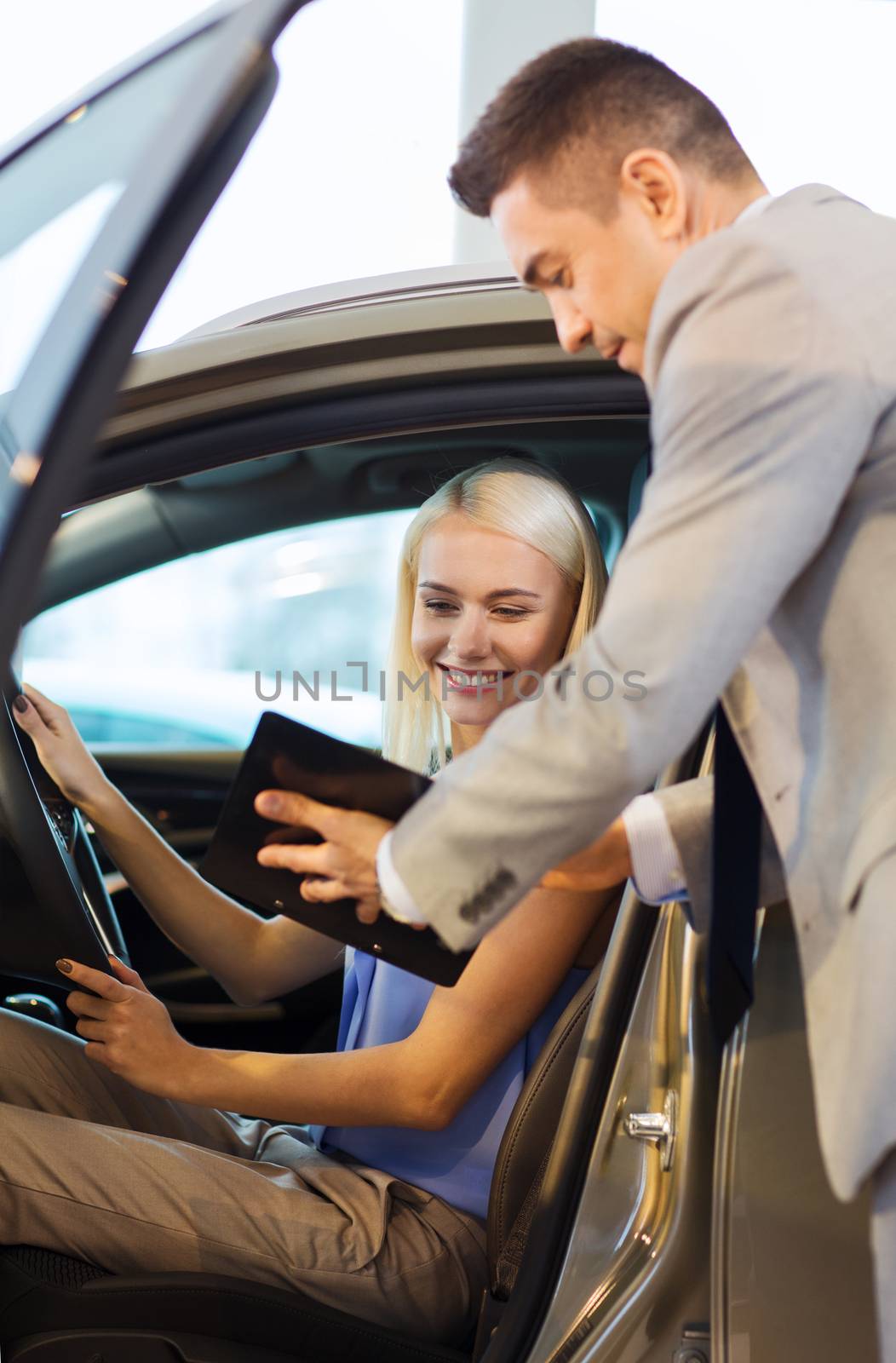 happy woman with car dealer in auto show or salon by dolgachov