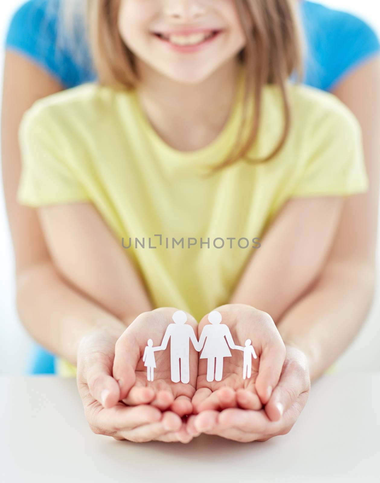 people, charity, family and care concept - close up of woman and girl hands holding paper family cutout