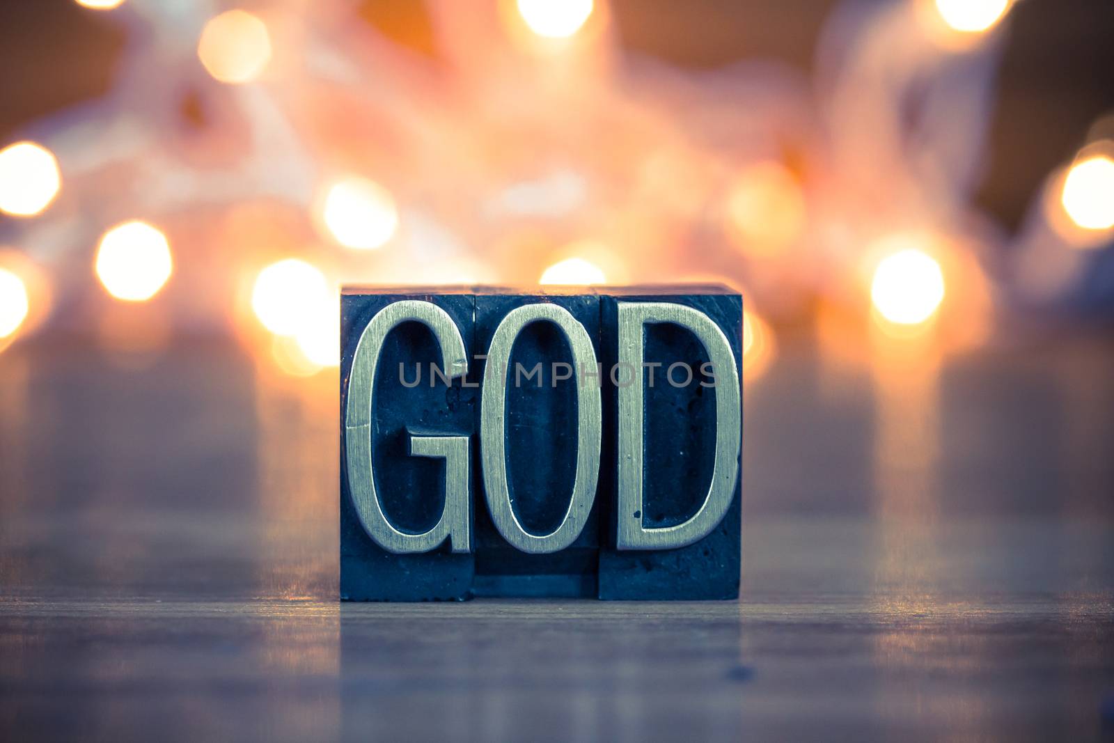 The word GOD written in vintage metal letterpress type on a soft backlit background.