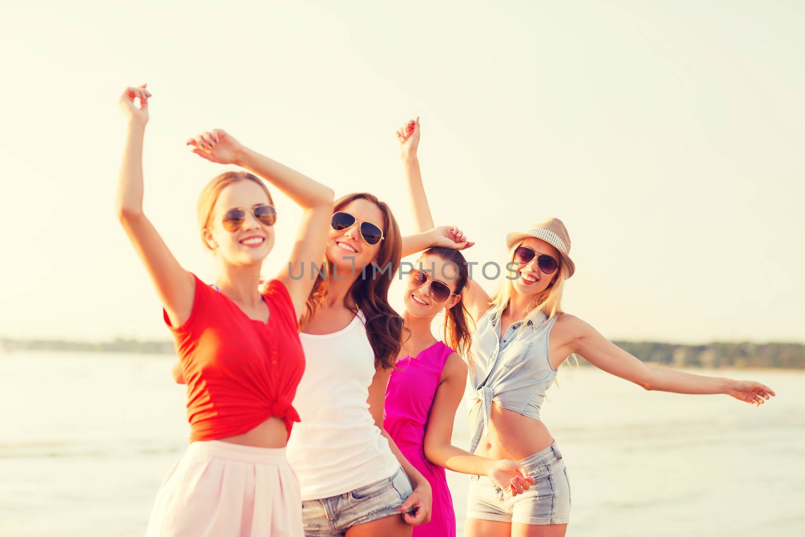 group of smiling women dancing on beach by dolgachov