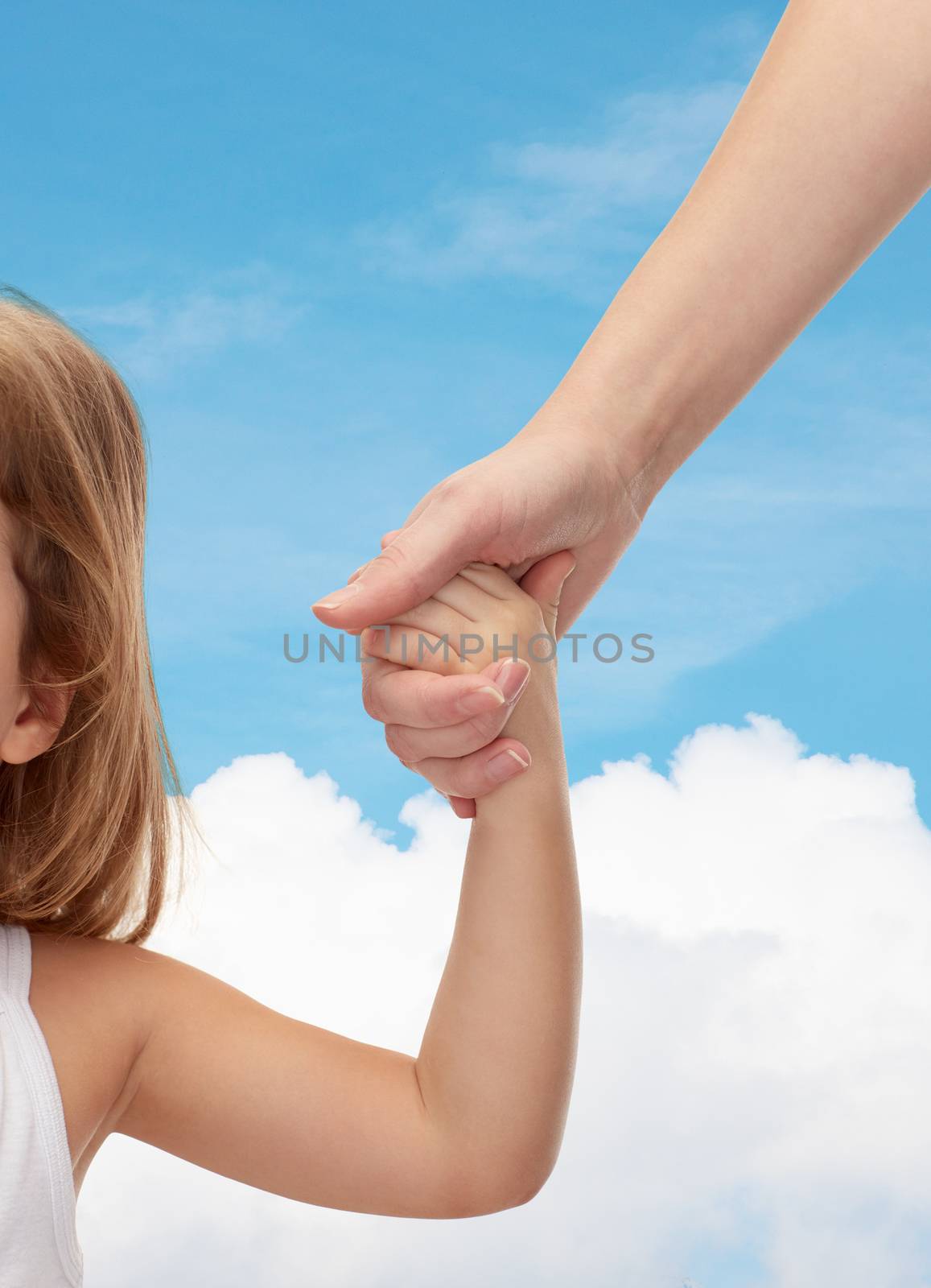 people, charity, family and adoption concept - close up of woman and little girl holding hands over blue sky and cloud background