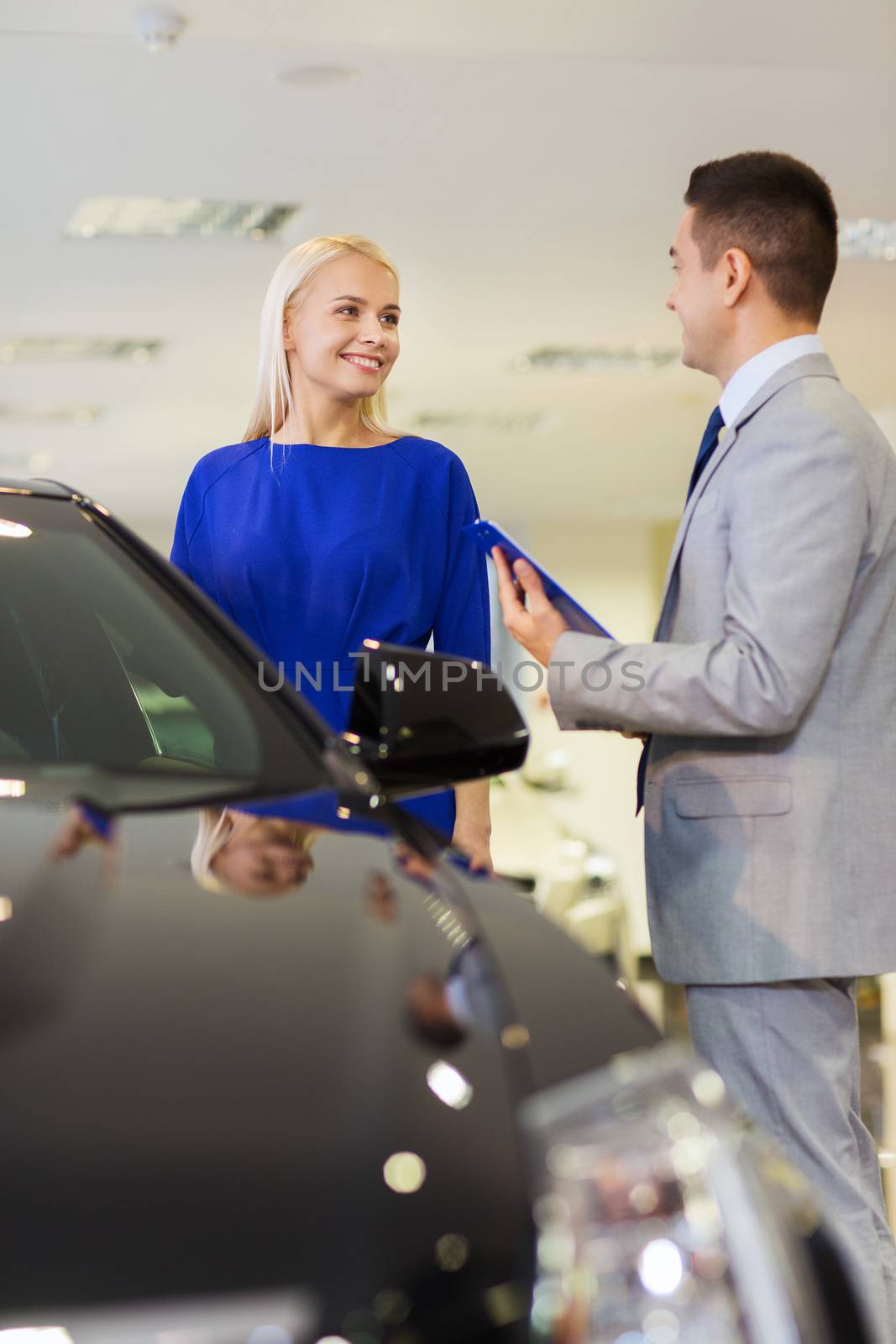 happy woman with car dealer in auto show or salon by dolgachov