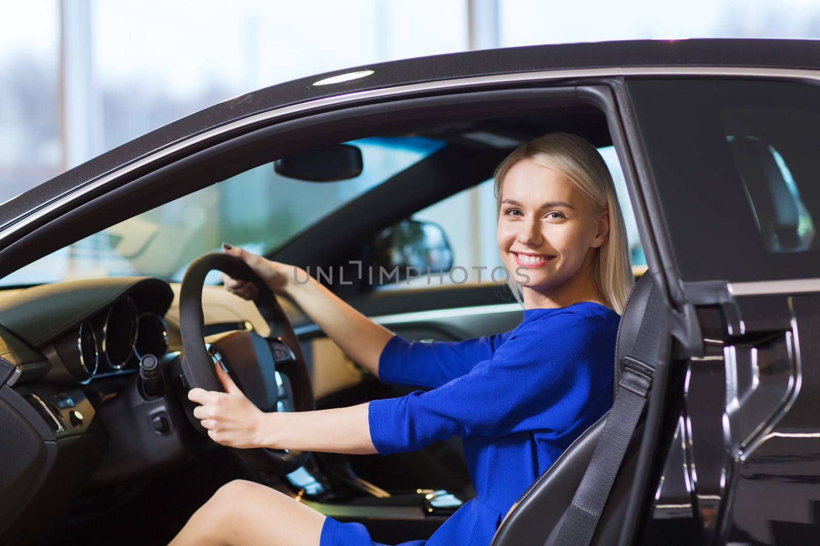 happy woman inside car in auto show or salon by dolgachov