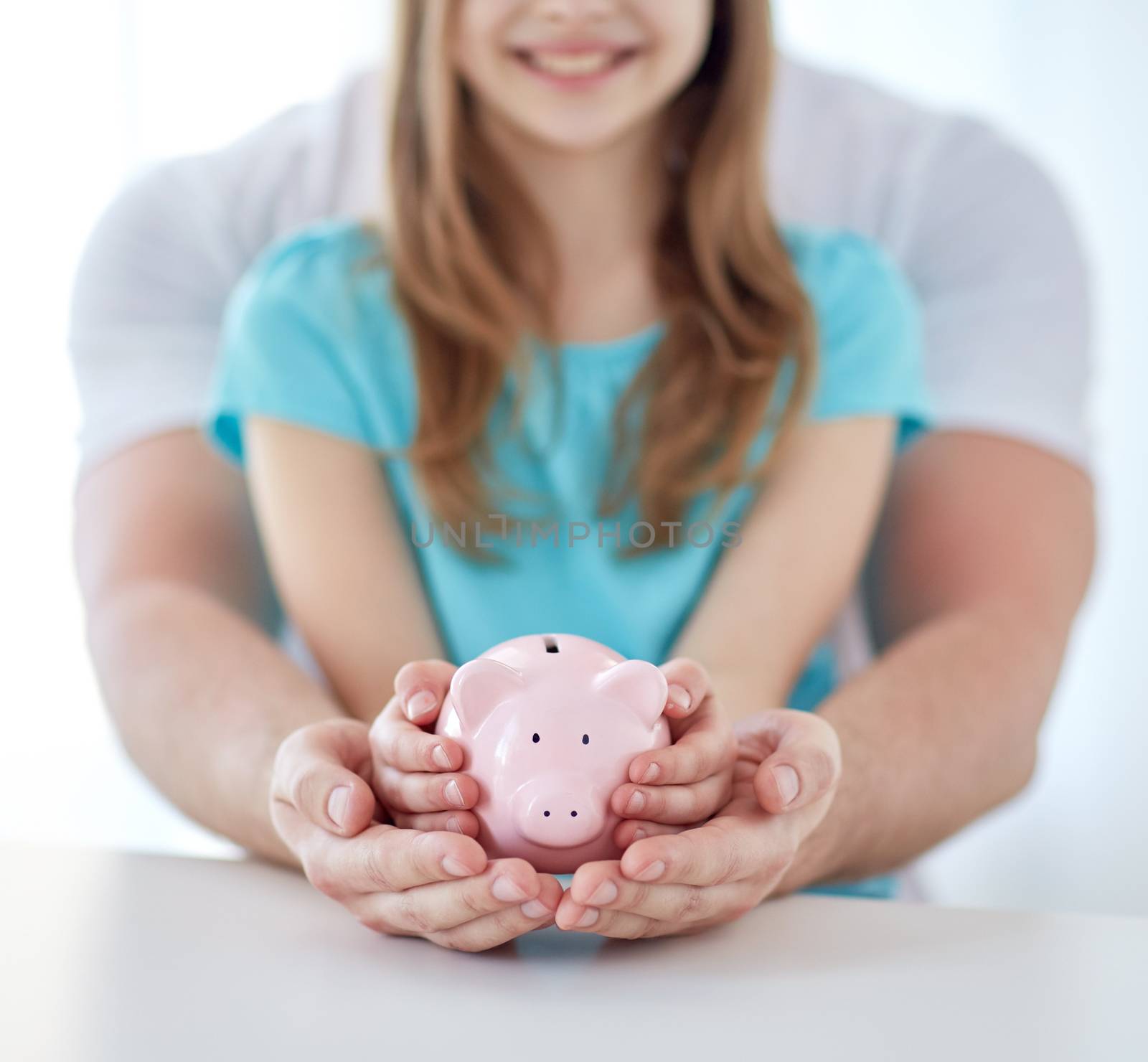 family, children, money, investments and people concept - close up of father and daughter hands holding pink piggy bank