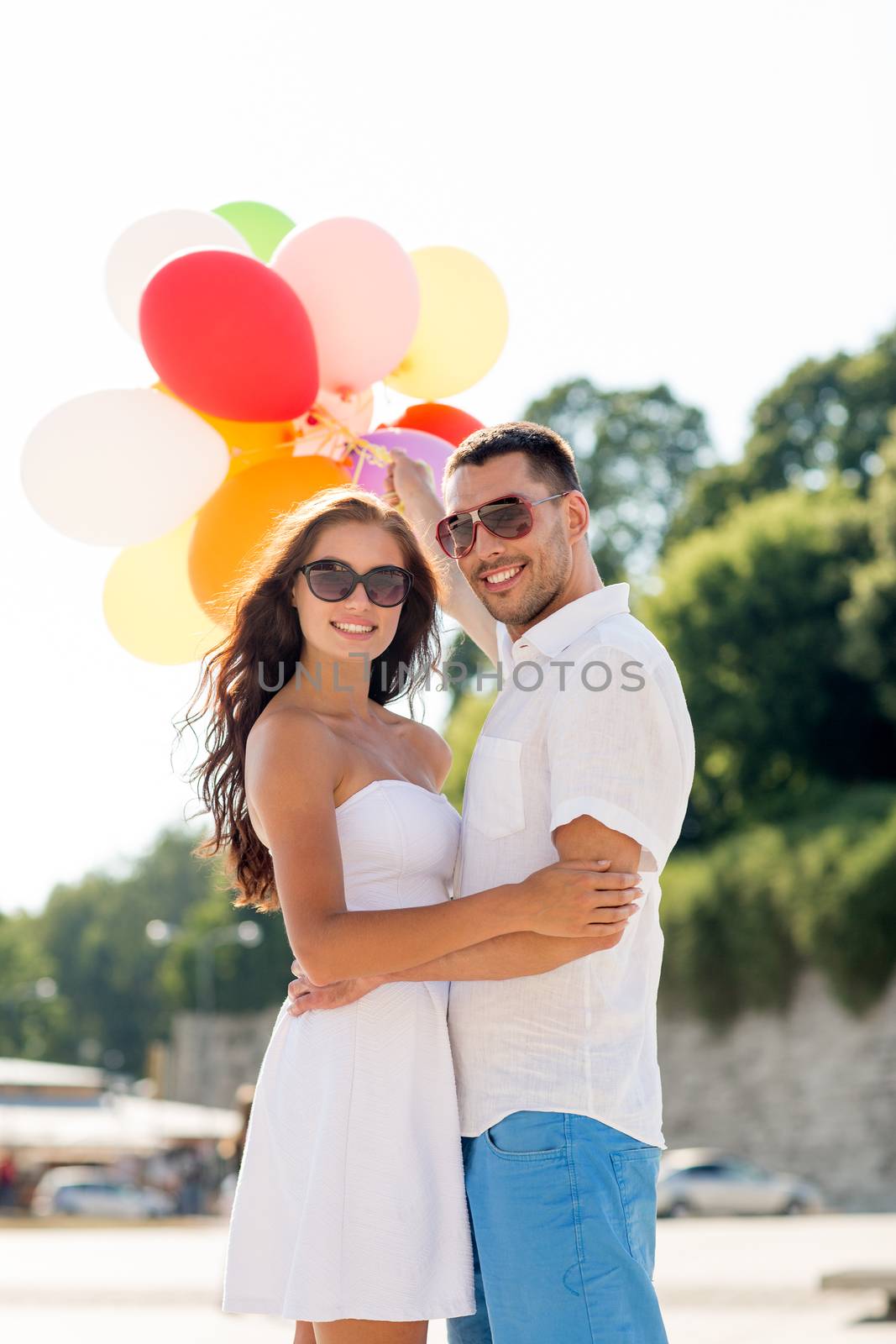 love, wedding, summer, dating and people concept - smiling couple wearing sunglasses with balloons hugging in park