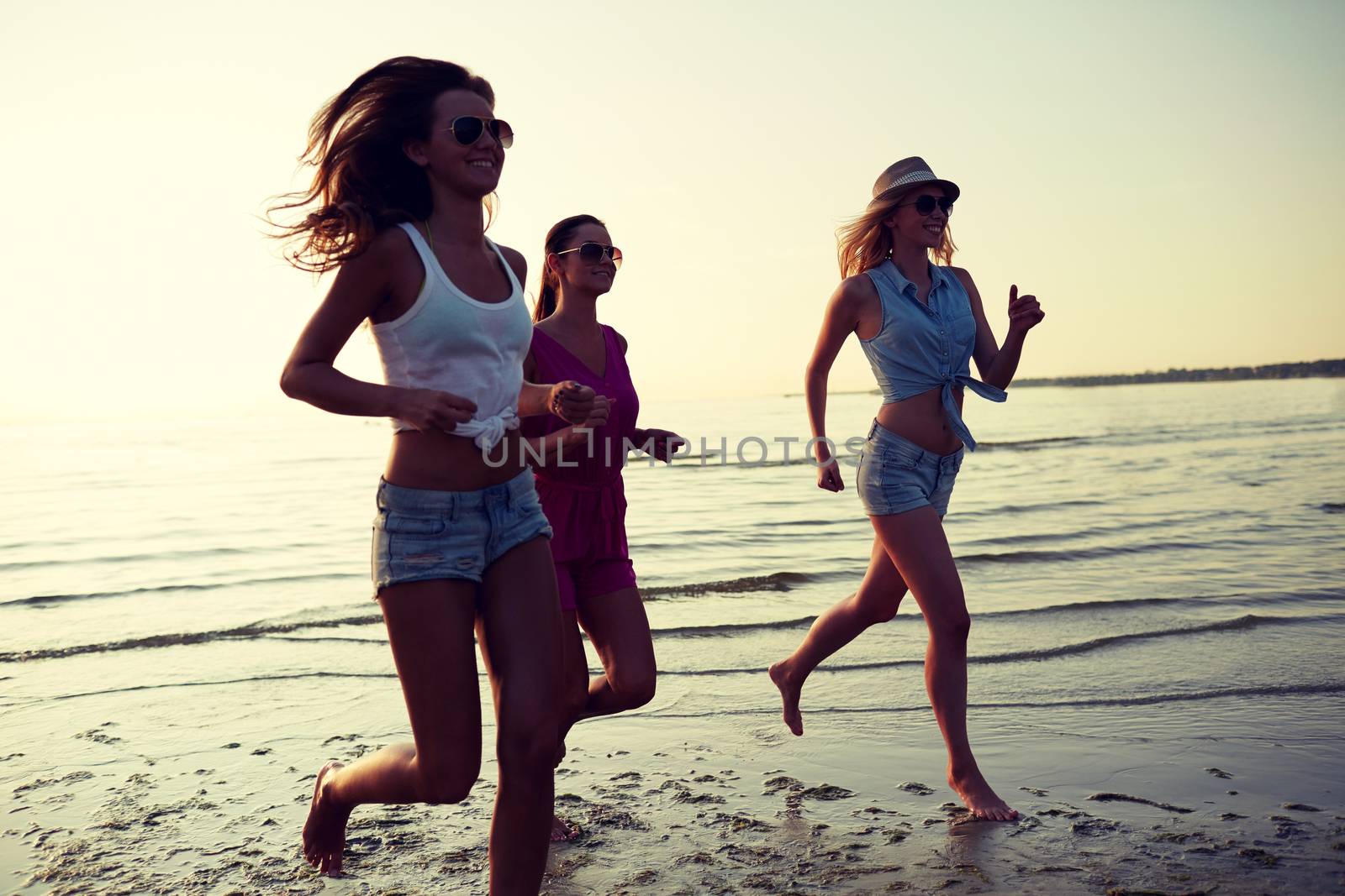 group of smiling women running on beach by dolgachov