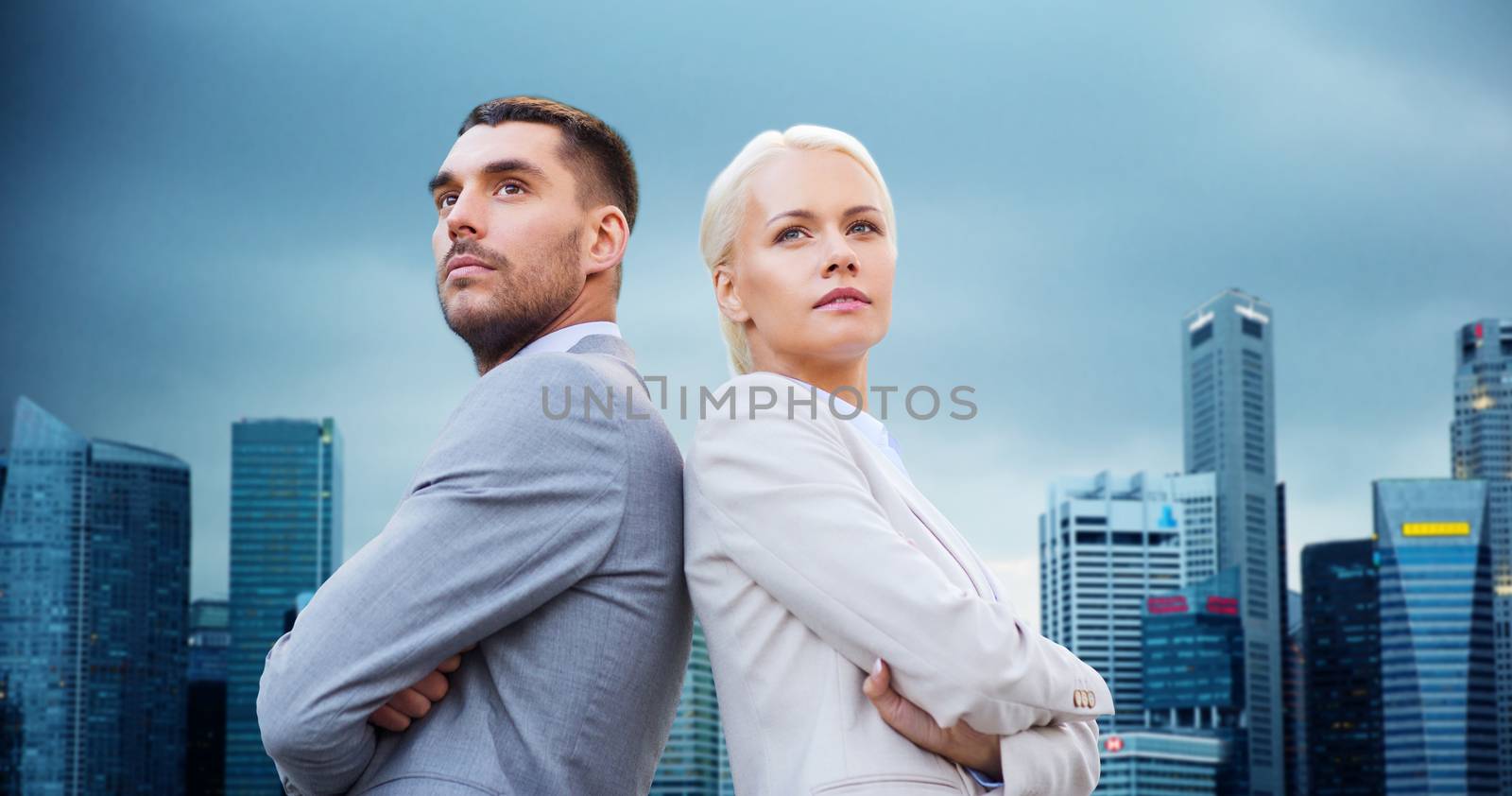 business, partnership, teamwork and people concept - businessman and businesswoman standing over city buildings background