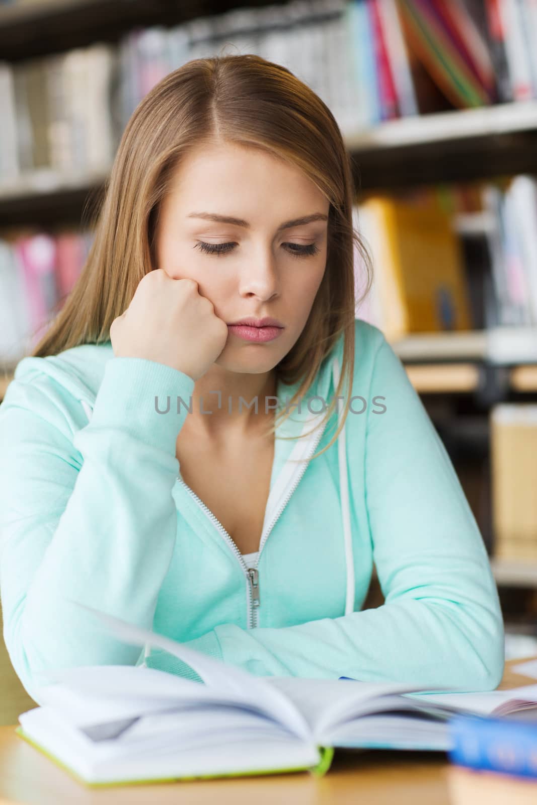 people, knowledge, education and school concept - student girl reading book in library