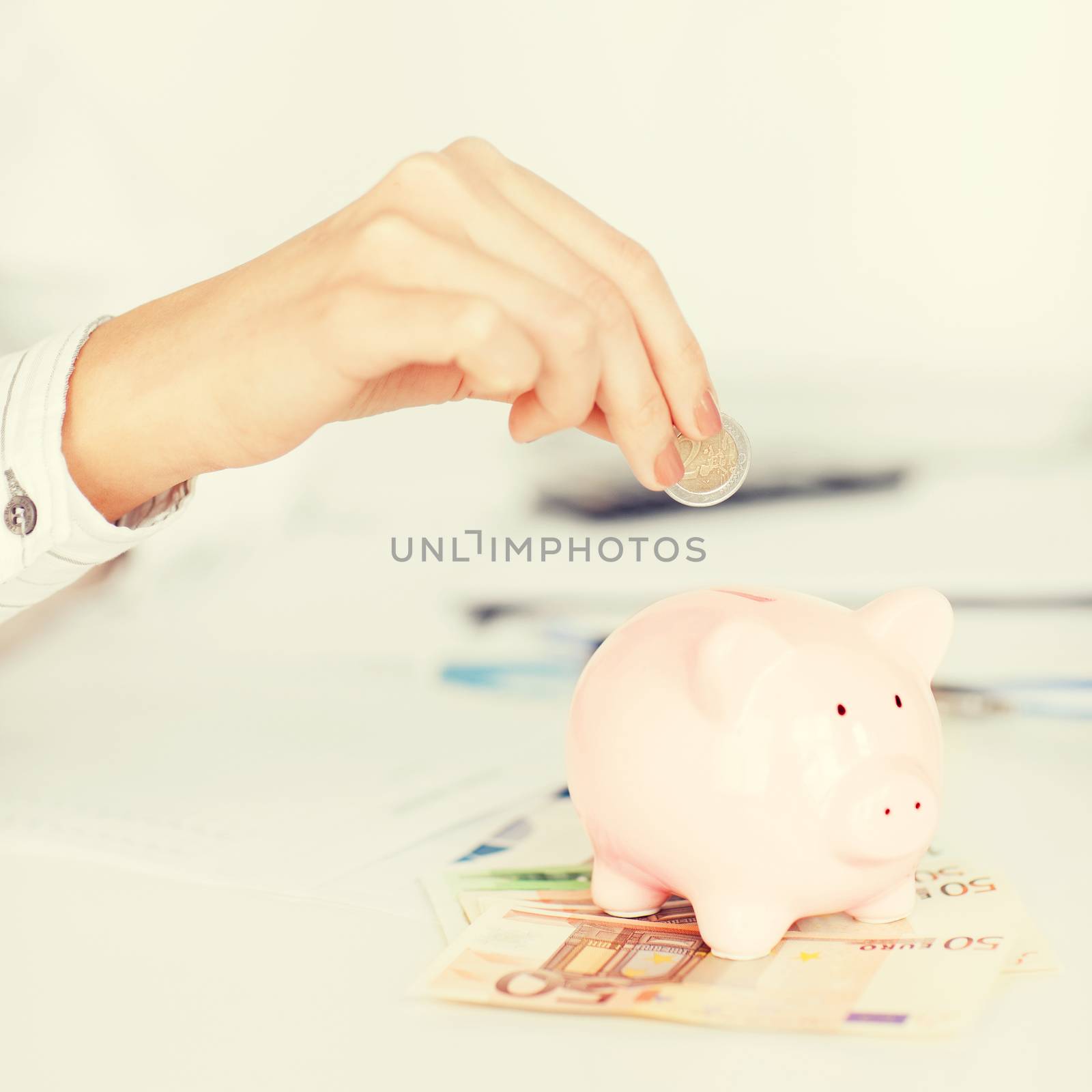 business, office, household, school, tax and education concept - woman hand putting coin into small piggy bank