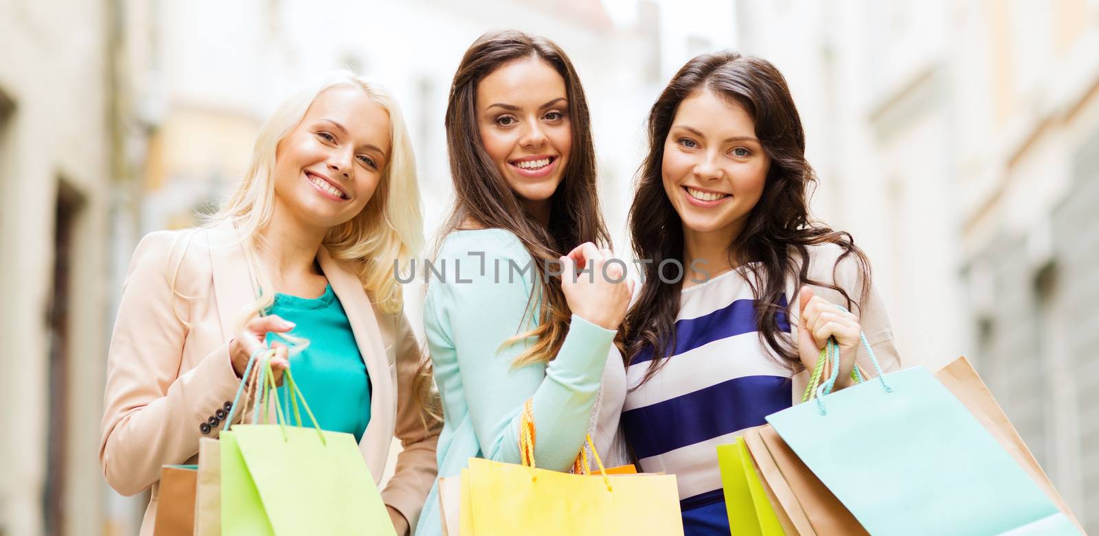 shopping and tourism concept - beautiful girls with shopping bags in ctiy