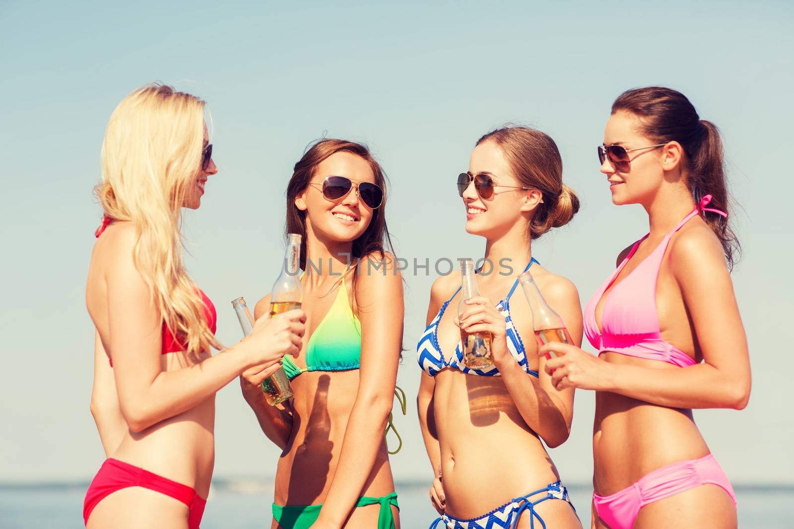 group of smiling young women drinking on beach by dolgachov