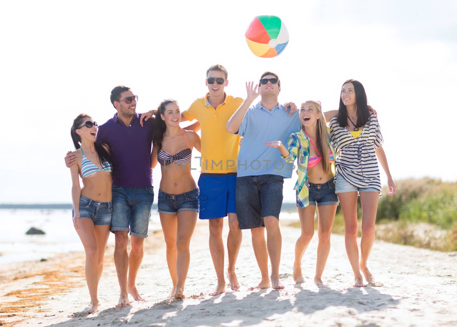 summer holidays, vacation, tourism, travel and people concept - group of happy friends playing with inflatable ball walking along beach