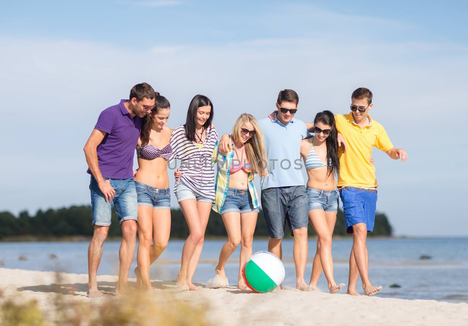 group of happy friends walking along beach by dolgachov