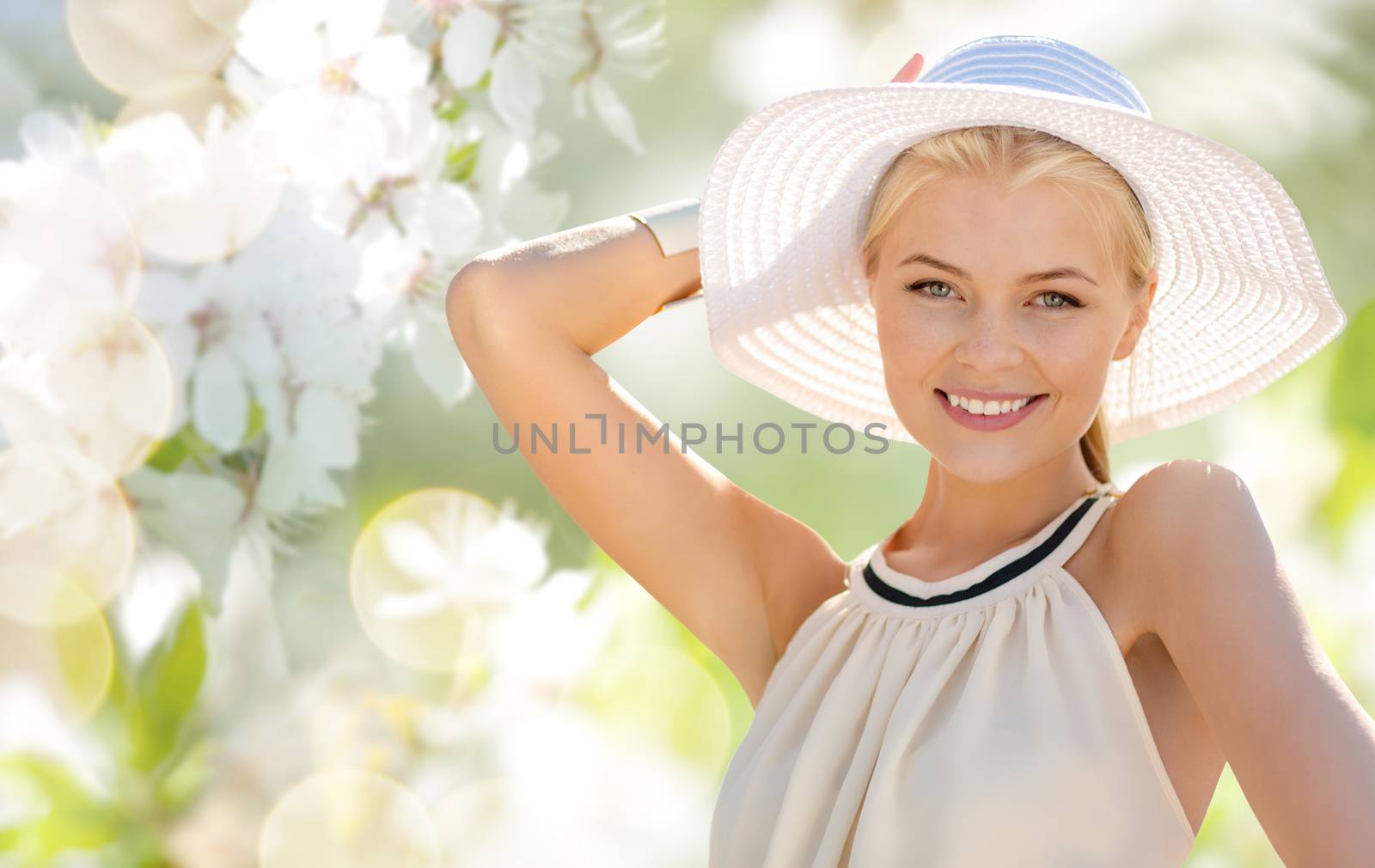 fashion, people and summer holidays concept - beautiful woman in hat and dress over green blooming garden background