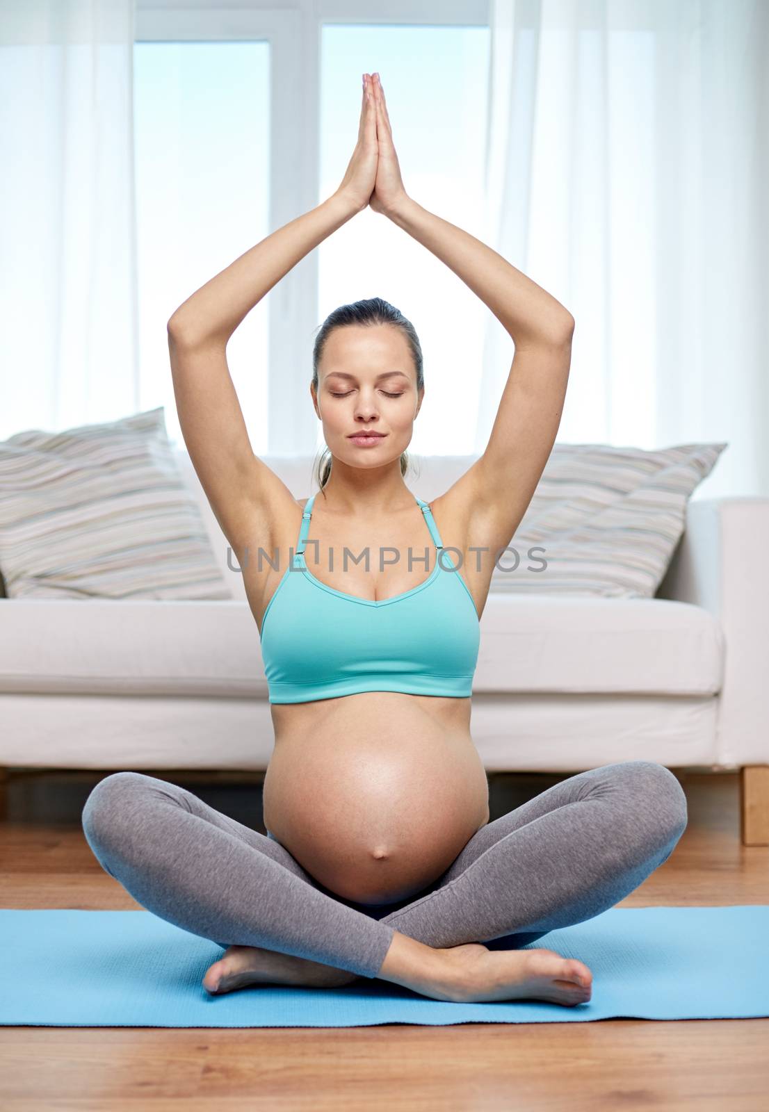happy pregnant woman meditating at home by dolgachov