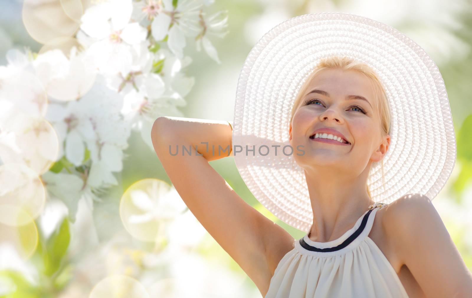 fashion, people and summer holidays concept - beautiful woman in hat and dress over green blooming garden background