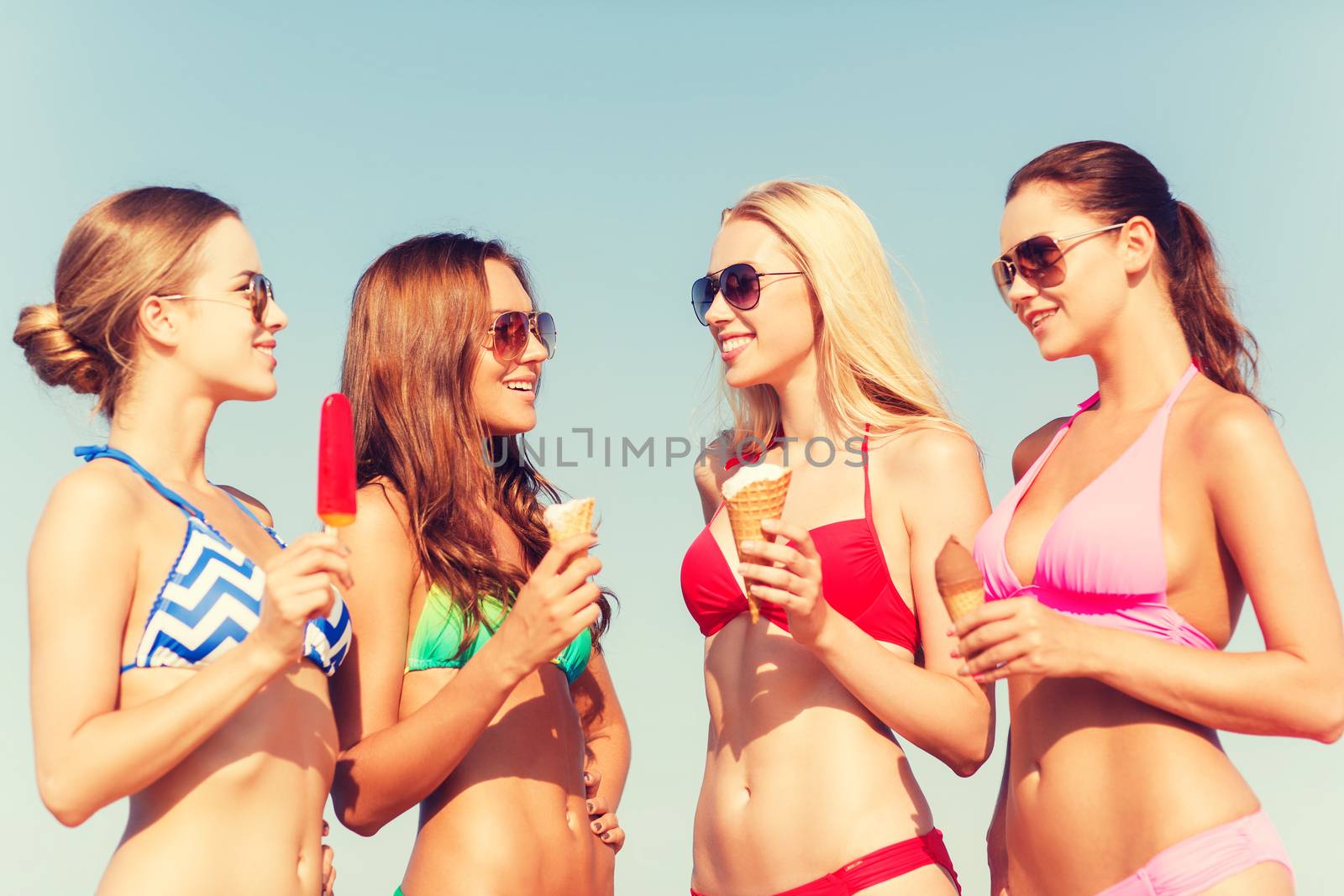 summer vacation, holidays, food, travel and people concept - group of smiling young women eating ice cream on beach