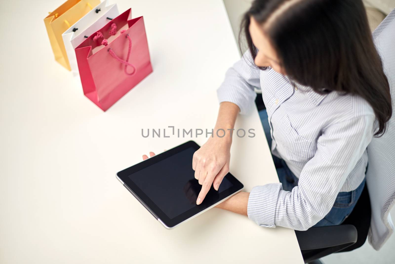 business, technology, sale, communication and people concept - close up of woman with tablet pc computer and shopping bags at office or home