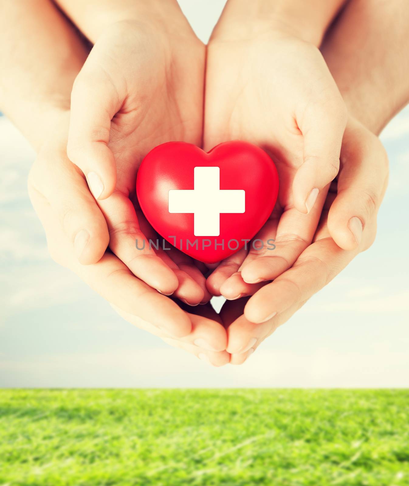 family health, charity and medicine concept - male and female hands holding red heart with cross sign