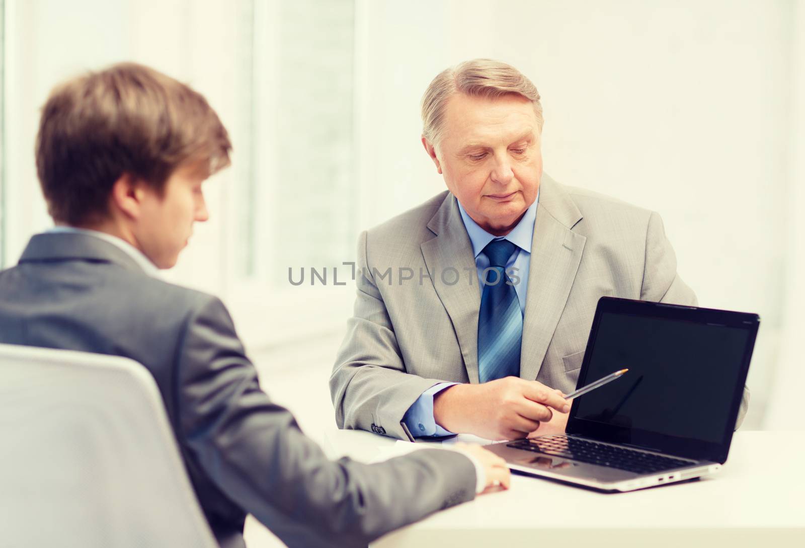 business, advertisement, technology and office concept - older man and young man with laptop computer in office