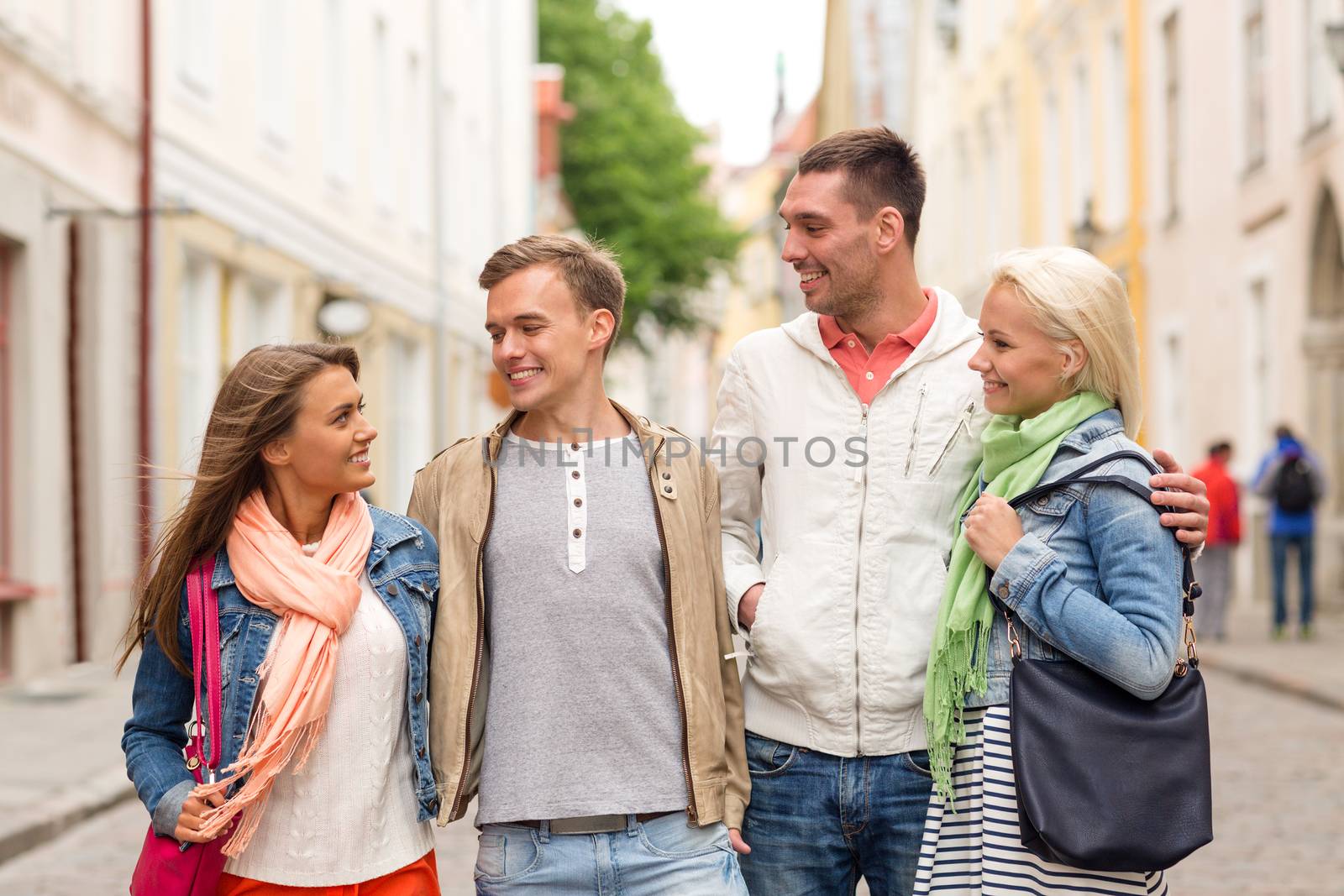 group of smiling friends walking in the city by dolgachov