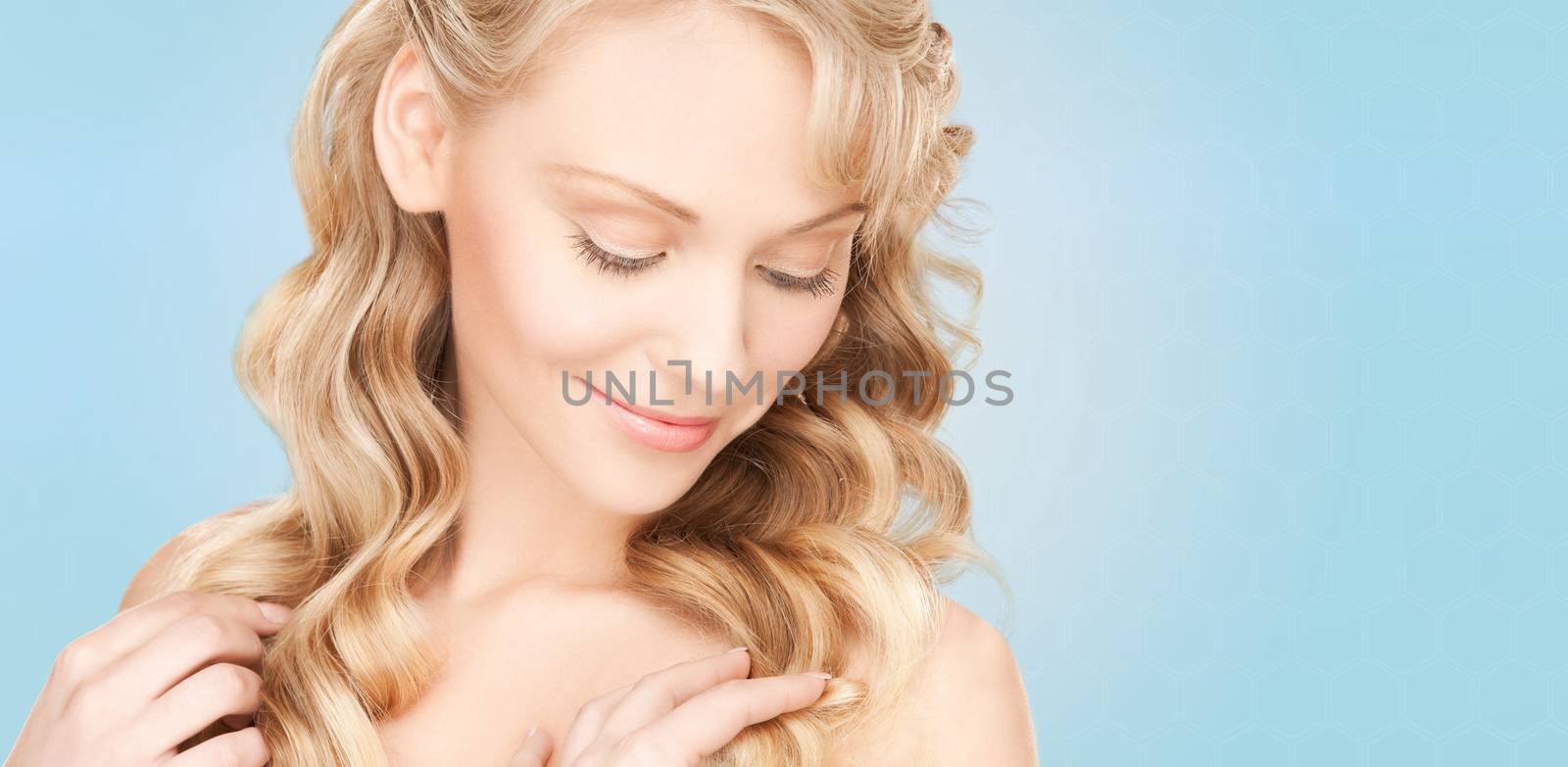 beauty, people, hair care and health concept - beautiful young woman face with long wavy hair over blue background