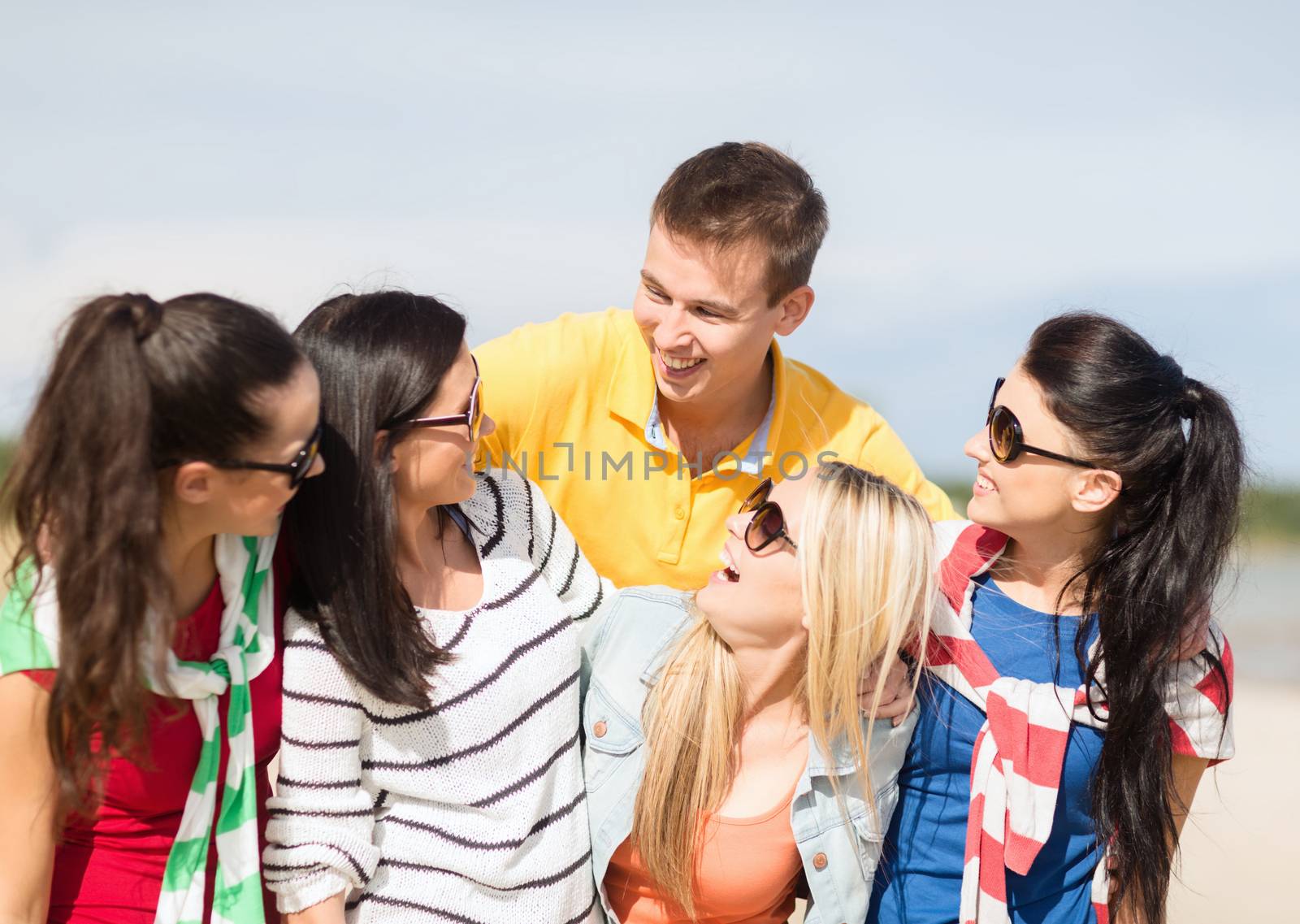 summer holidays, vacation, tourism, travel and people concept - group of happy friends having fun and talking on beach