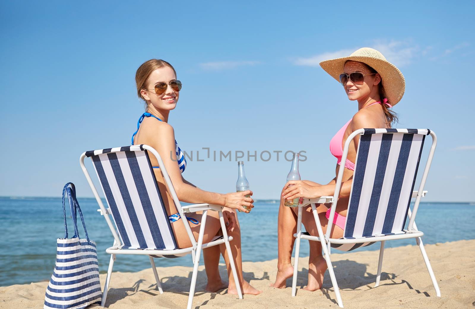 happy women sunbathing in lounges on beach by dolgachov