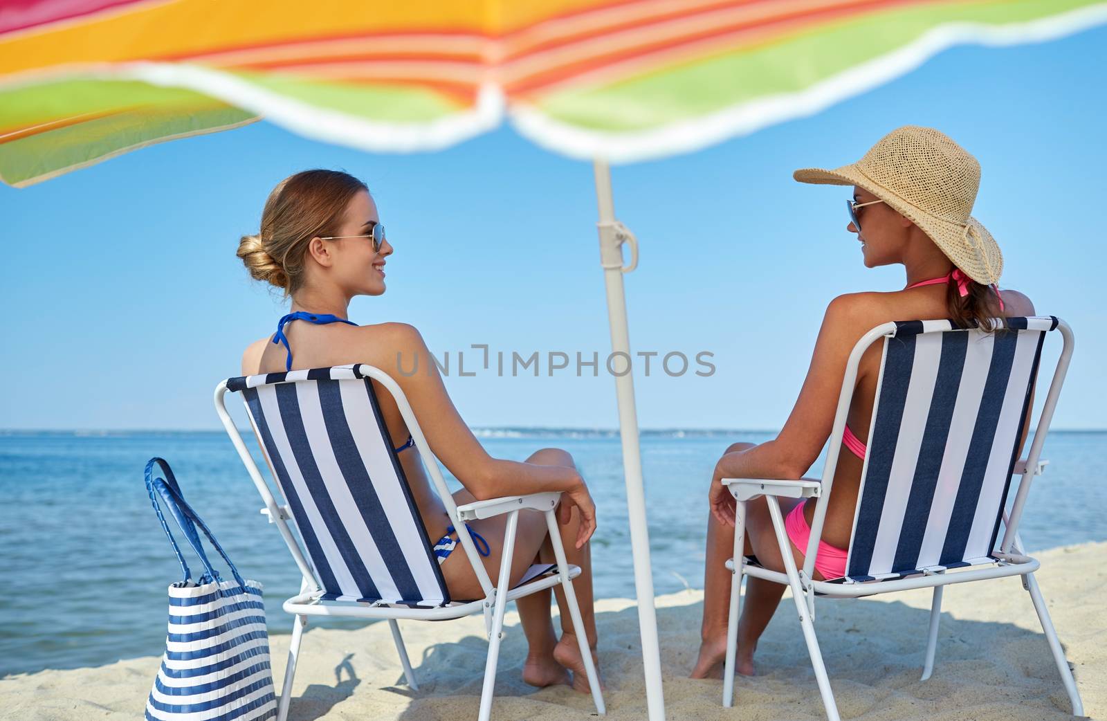 happy women sunbathing in lounges on beach by dolgachov