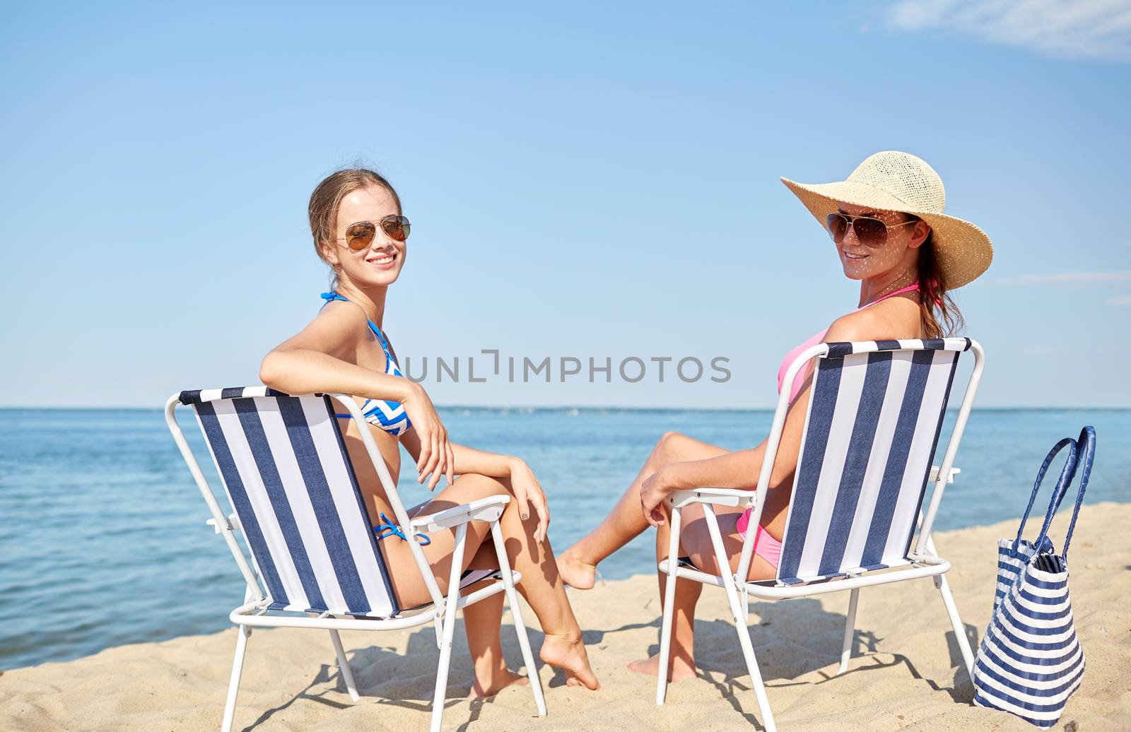 happy women sunbathing in lounges on beach by dolgachov