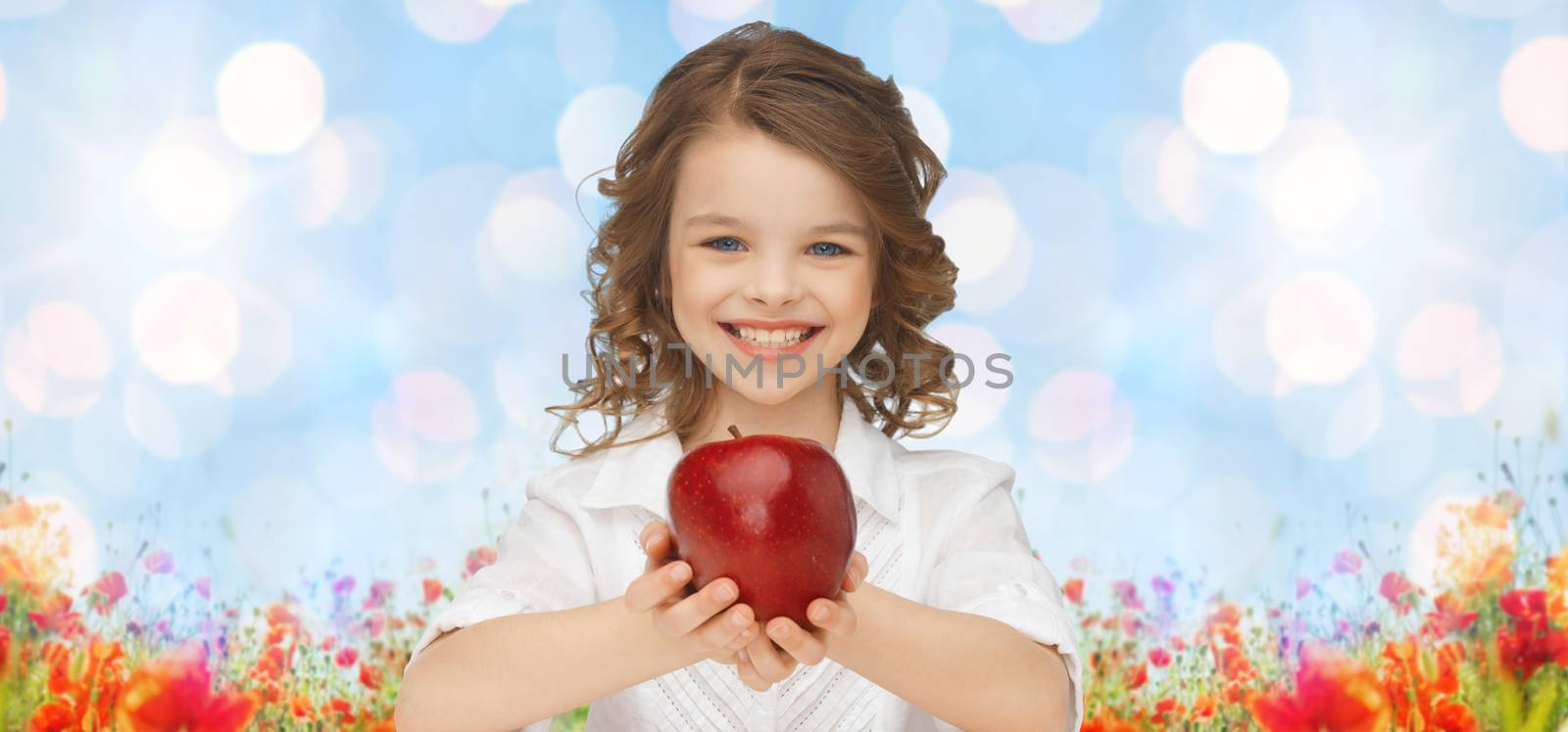people, children, healthy eating, summer and food concept- happy girl holding red apple over blue sky and poppies field n background