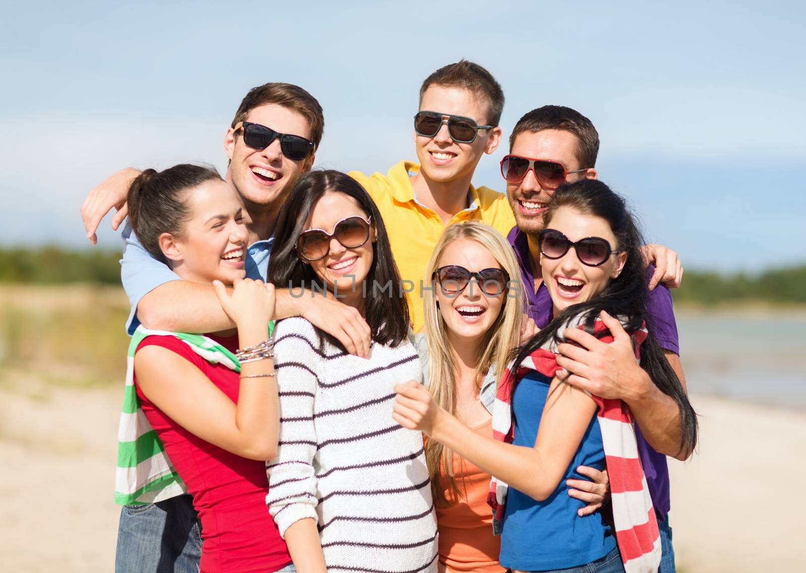 summer holidays, vacation, tourism, travel and people concept - group of happy friends having fun and hugging on beach