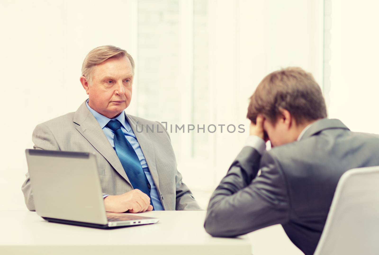 older man and young man having argument in office by dolgachov