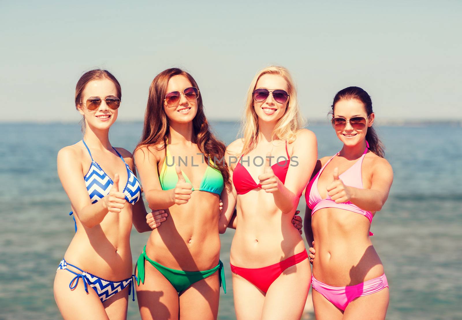 summer vacation, holidays, travel and people concept - group of smiling young women showing thumbs up on beach