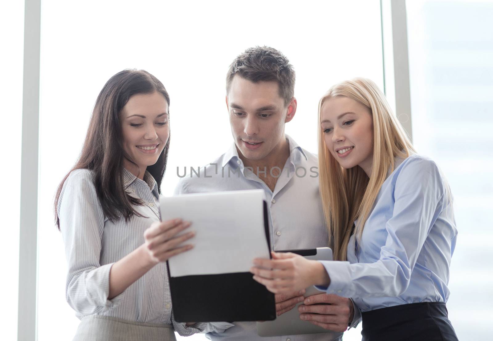 business and office concept - smiling business team looking at clipboard