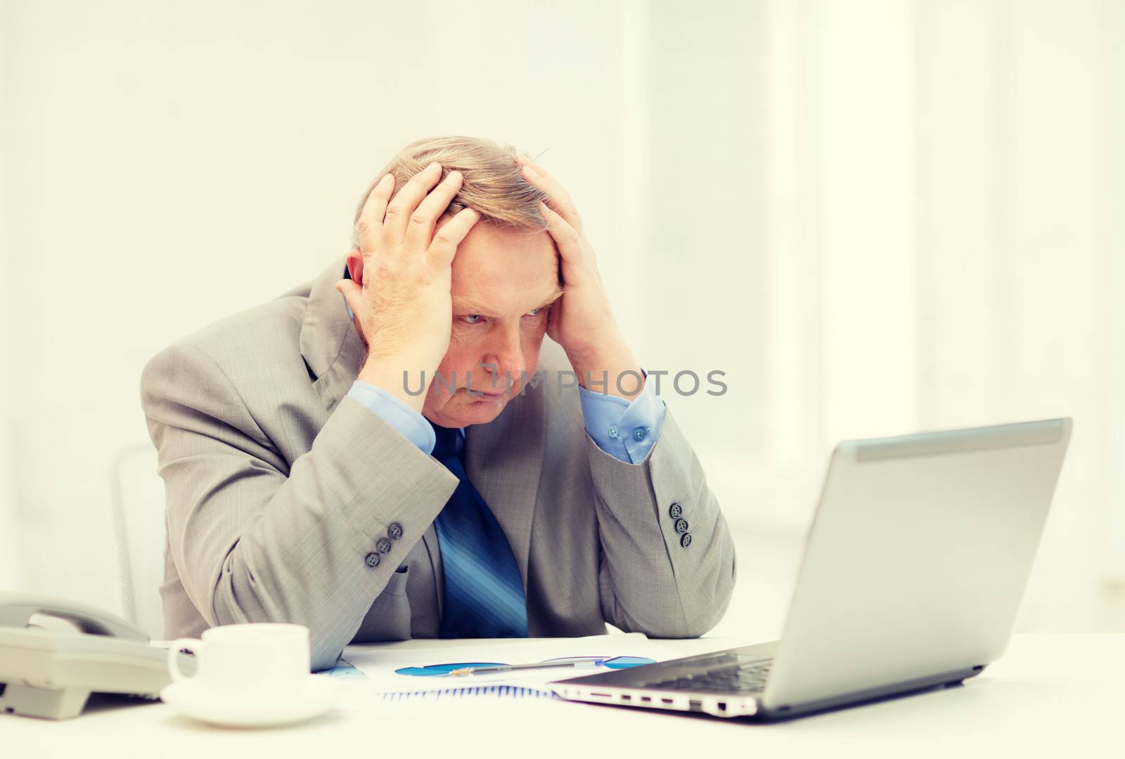 business, technologym communication and office concept - upset older businessman with laptop, charts, coffee and telephone in office