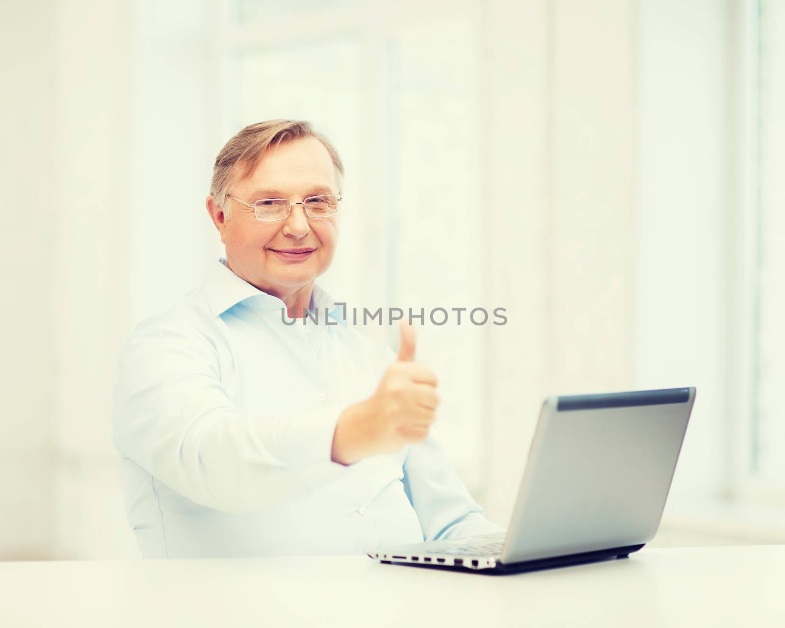 technology, oldness and lifestyle concept - old man in eyeglasses with laptop computer at home showing thumbs up
